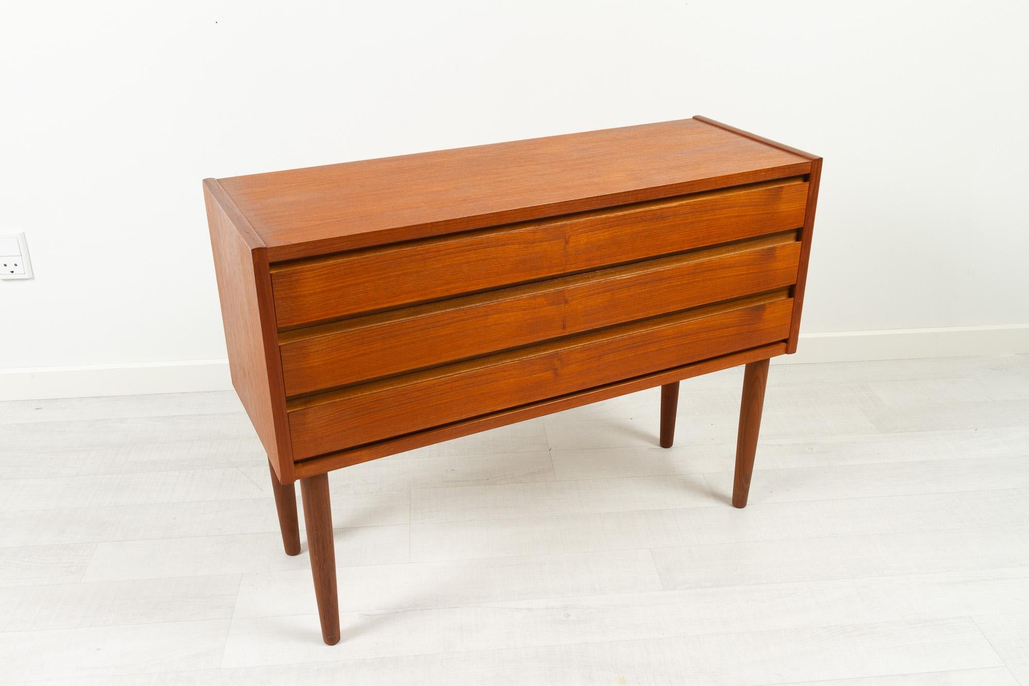 Vintage Danish modern teak dresser, 1960s.
Elegant wide and low Danish chest of drawers with three wide drawers with recessed pulls. Standing on four round tapered legs. Beautiful teak veneer with nice grain pattern.
Very good condition. Drawers