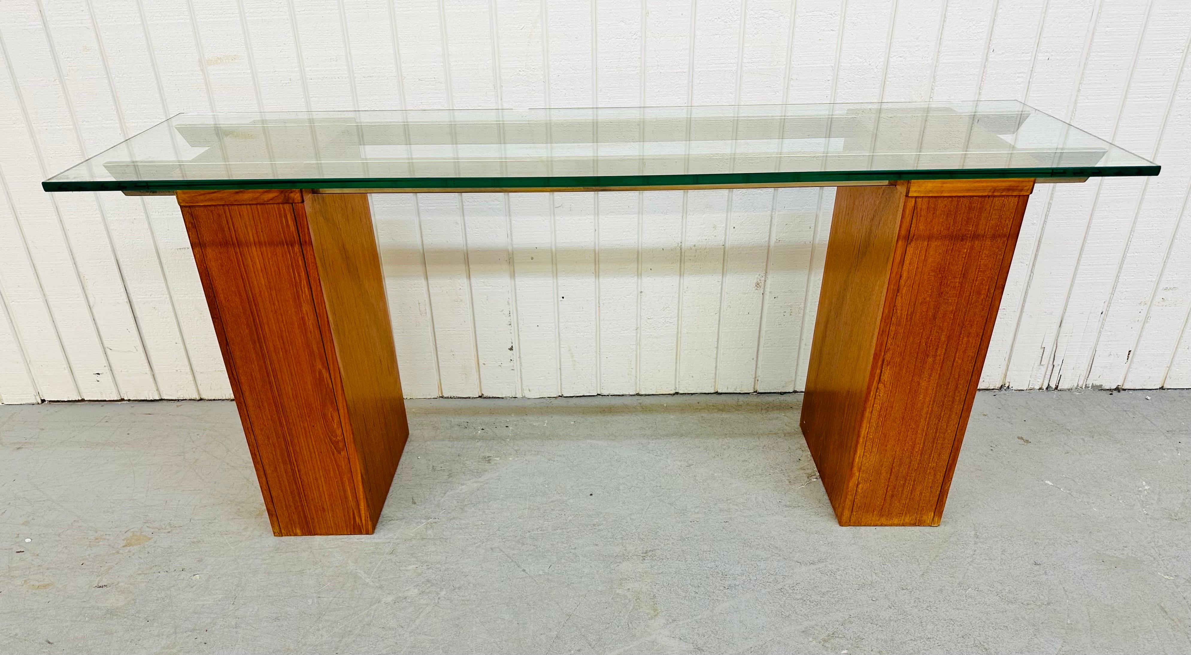 This listing is for a Danish Modern teak console table. Featuring a thick piece of rectangular glass that sits on teak pedestal bases that are connected by two brass stretchers. This is an exceptional combination of quality and design!