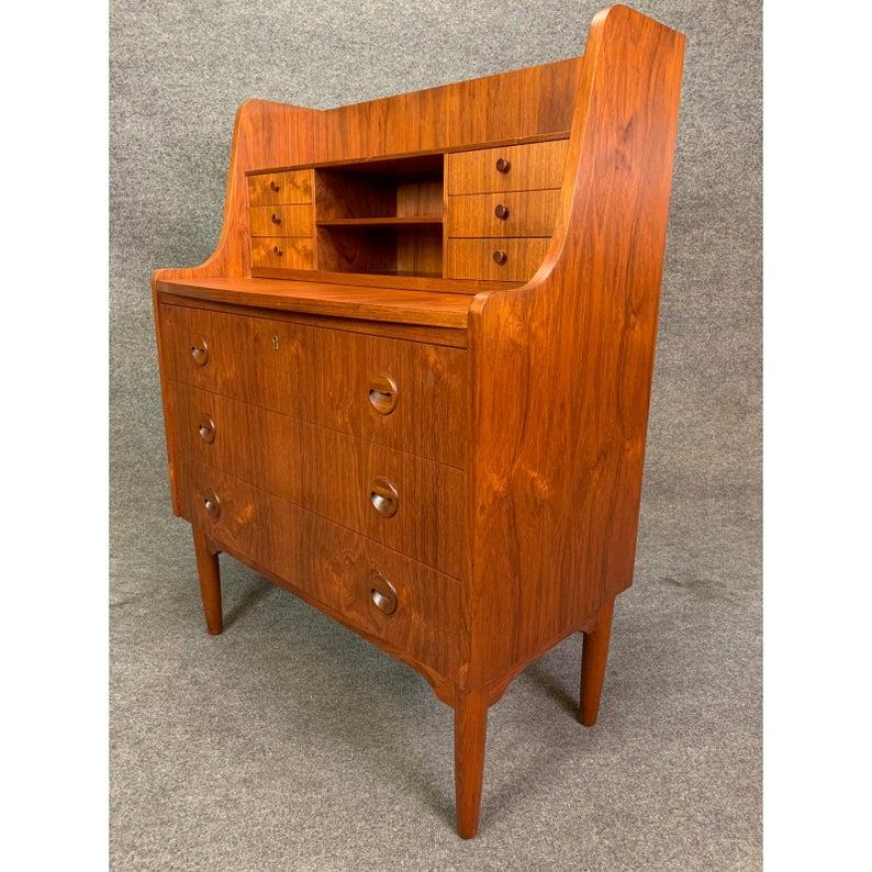 Here is a beautiful 1960s Scandinavian Modern secretary in teak wood recently imported from Denmark to California.
This versatile piece, with its vibrant wood grain, features on its top a bookshelf and two mail slots/cubbies flanked by two banks of
