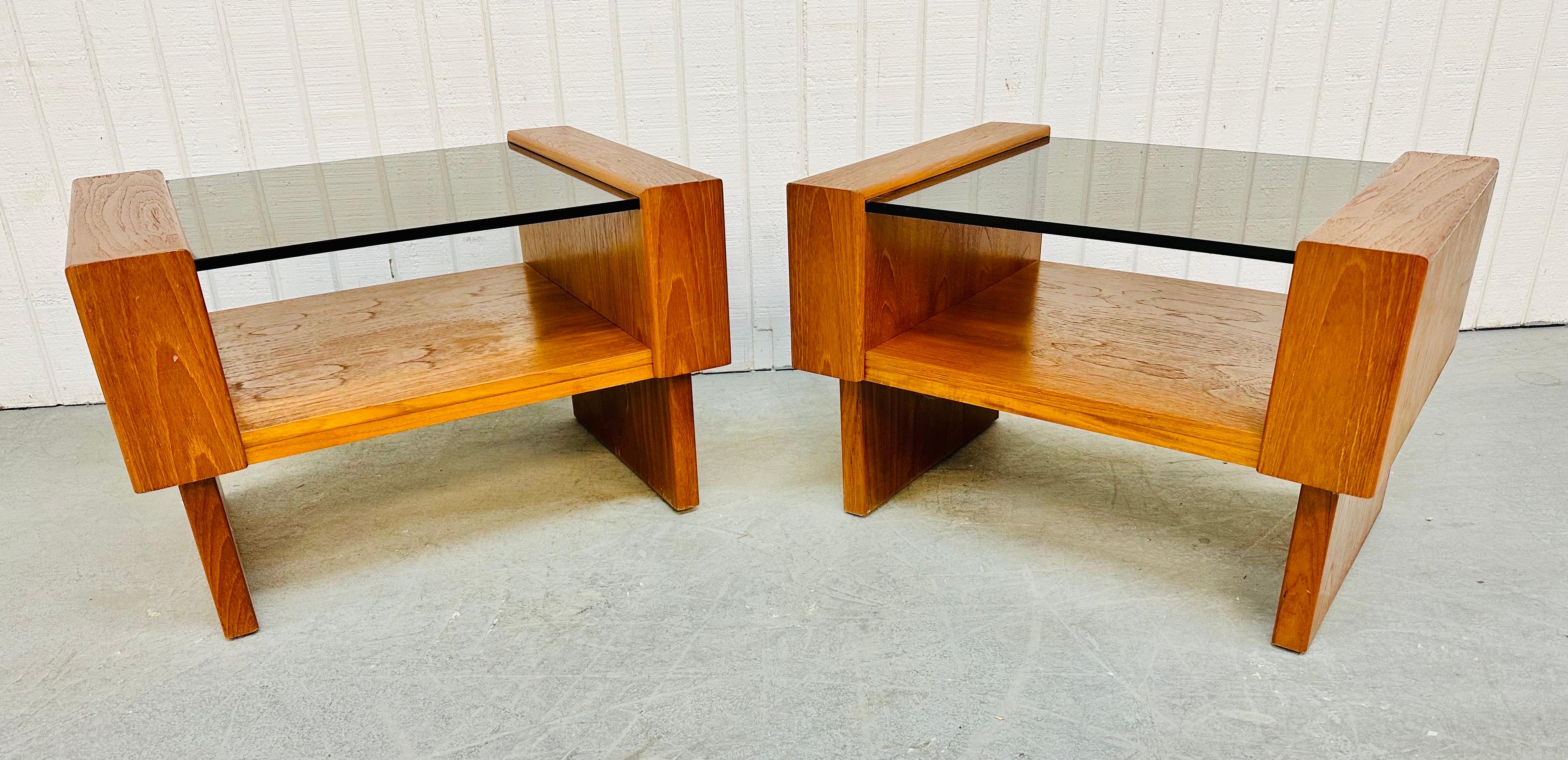 This listing is for a pair of vintage Danish Modern Teak Smoked Glass Side Tables. Featuring a rectangular design, teak base, smoked glass tops, and an open space under the glass for magazine storage.