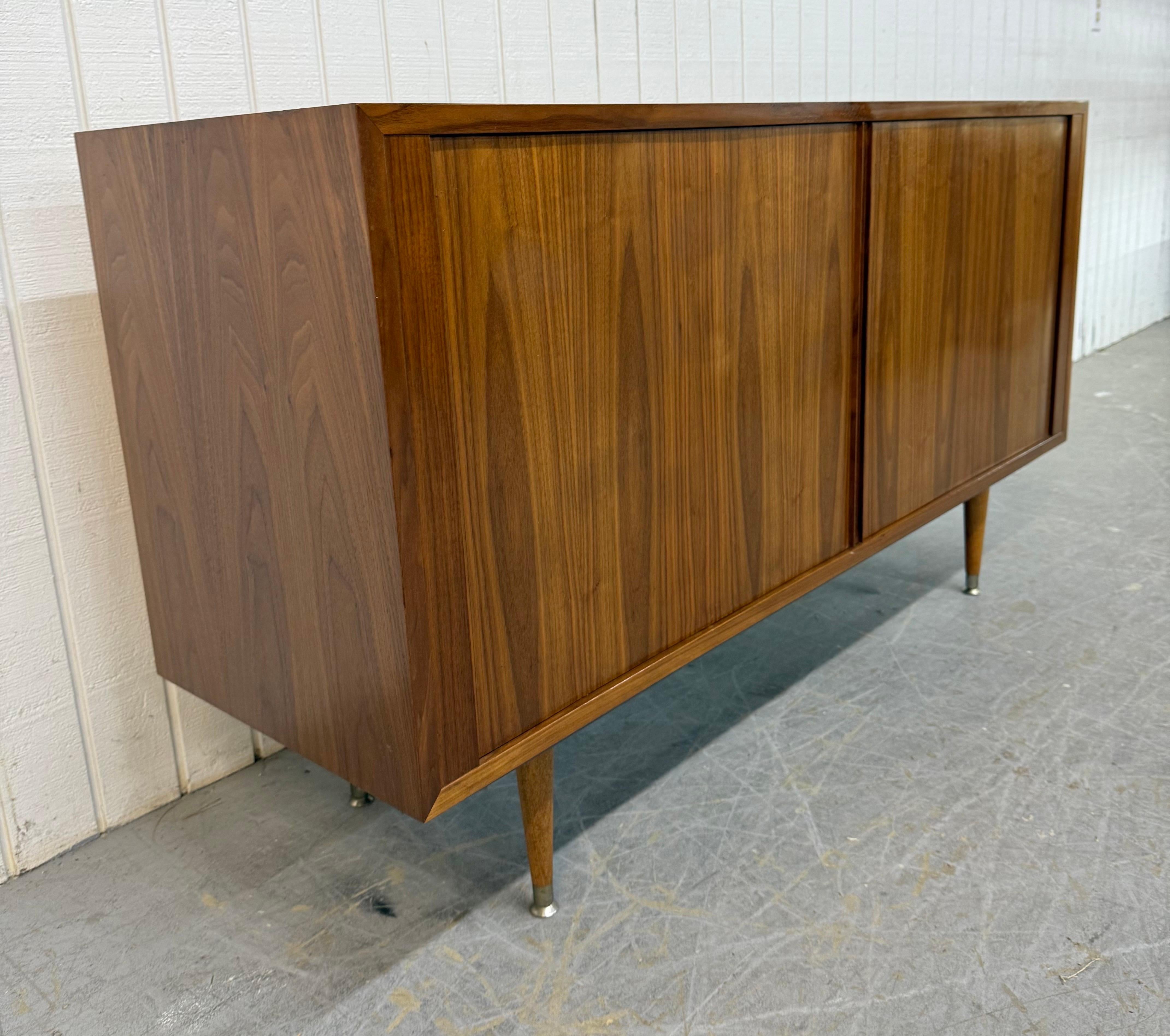 This listing is for a Vintage Danish Modern Teak Tambour Sideboard. Featuring a straight line design, sliding tambour doors that open up to storage space, modern legs, and a beautiful teak finish. This is an exceptional combination of quality and