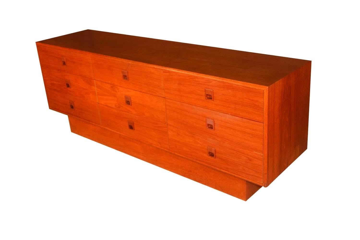 This vintage, Danish modern teak triple dresser features clean lines and solid rosewood sculpted finger pulls. A Classic Mid-Century Modern dresser featuring nine symmetrical spacious drawers with beautifully crafted carved rosewood finger pulls