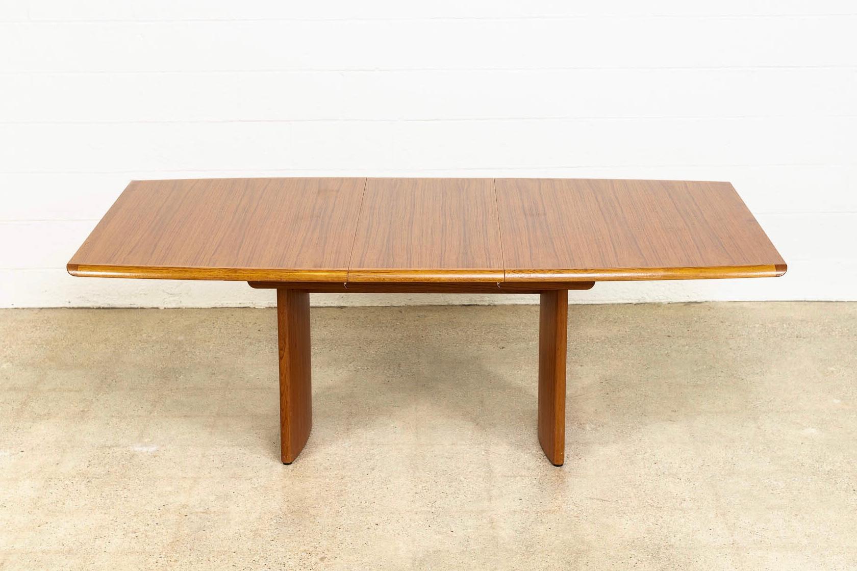 This vintage Mid-Century Modern teak wood expandable dining table was made in Denmark by Vejle Stole O.G. Møbelfabrik circa 1960. It has an elegant Minimalist aesthetic and a clean, unimposing Danish modern design. It is exceptionally crafted from