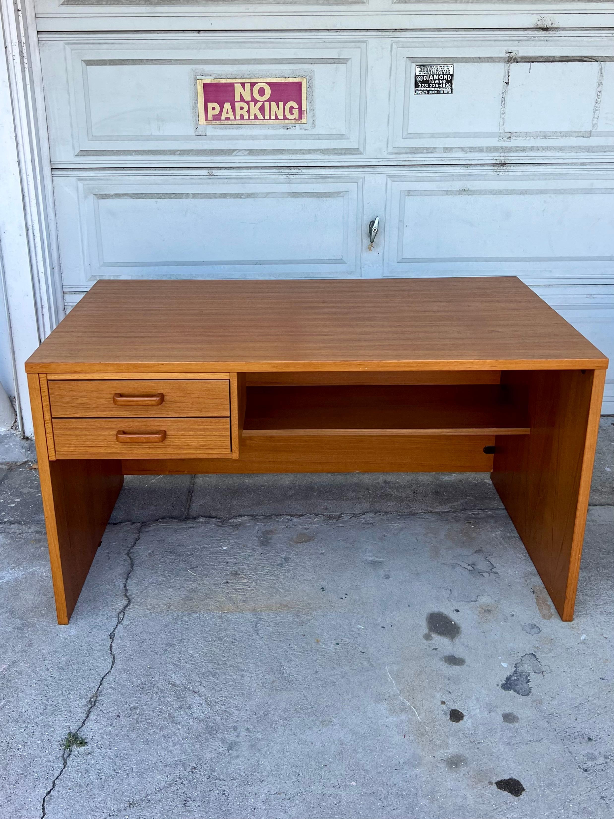 Presenting a sleek mini exec desk with function and design. Classic danish teak veneer desk (stamped made in Denmark) with two storage drawers. Teak veneer throughout with teak handles on the drawers. Drawers can be placed wherever desired under the