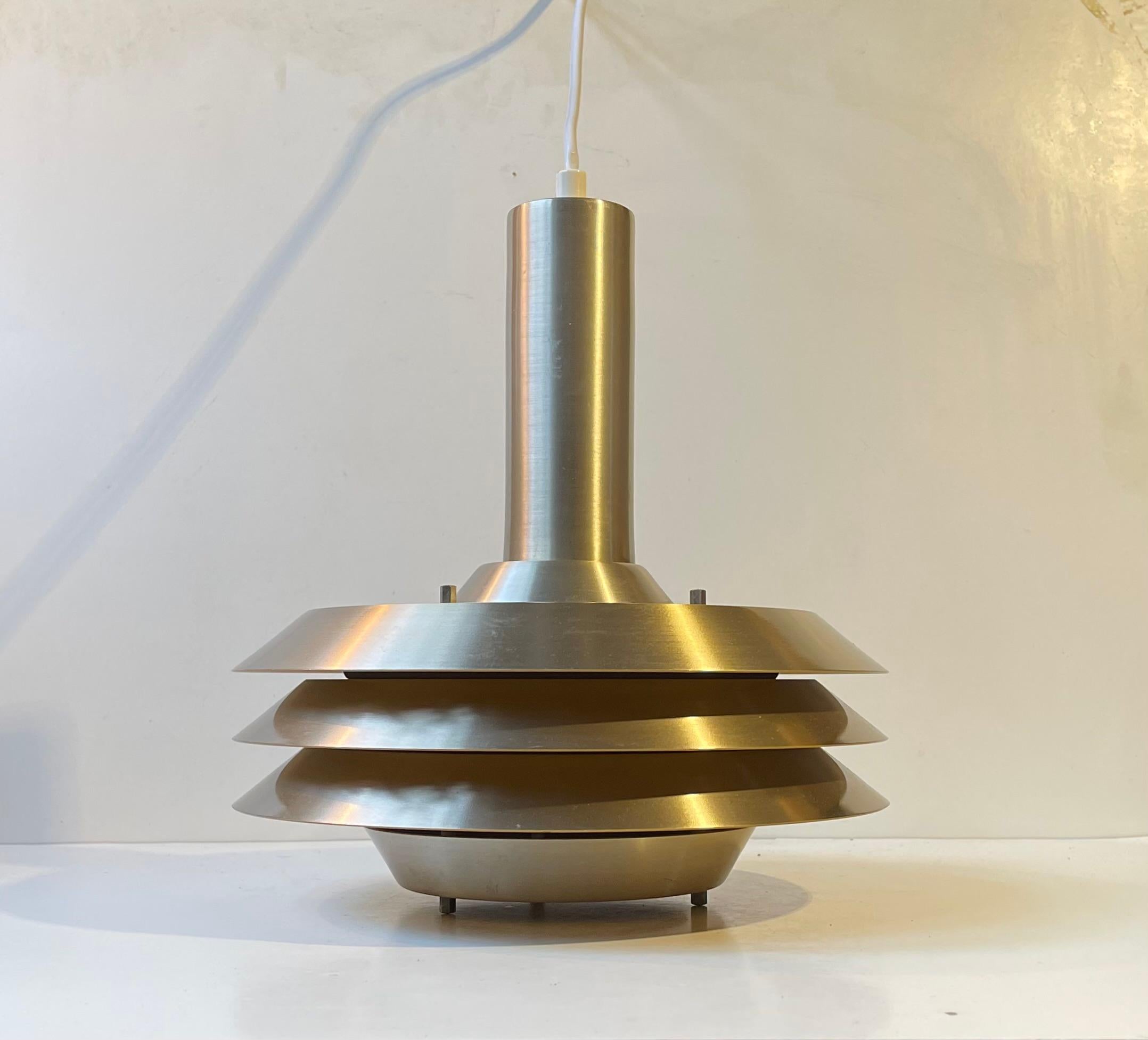 - Tiered spacey hanging ceiling light 
- Designed and manufactured by Lyskær Belysning in Denmark during the 1970s . Model number 705
- Reminiscent to the Trava series by Carl Thore 
- It is constructed of aluminium with a brushed brass finish 
-