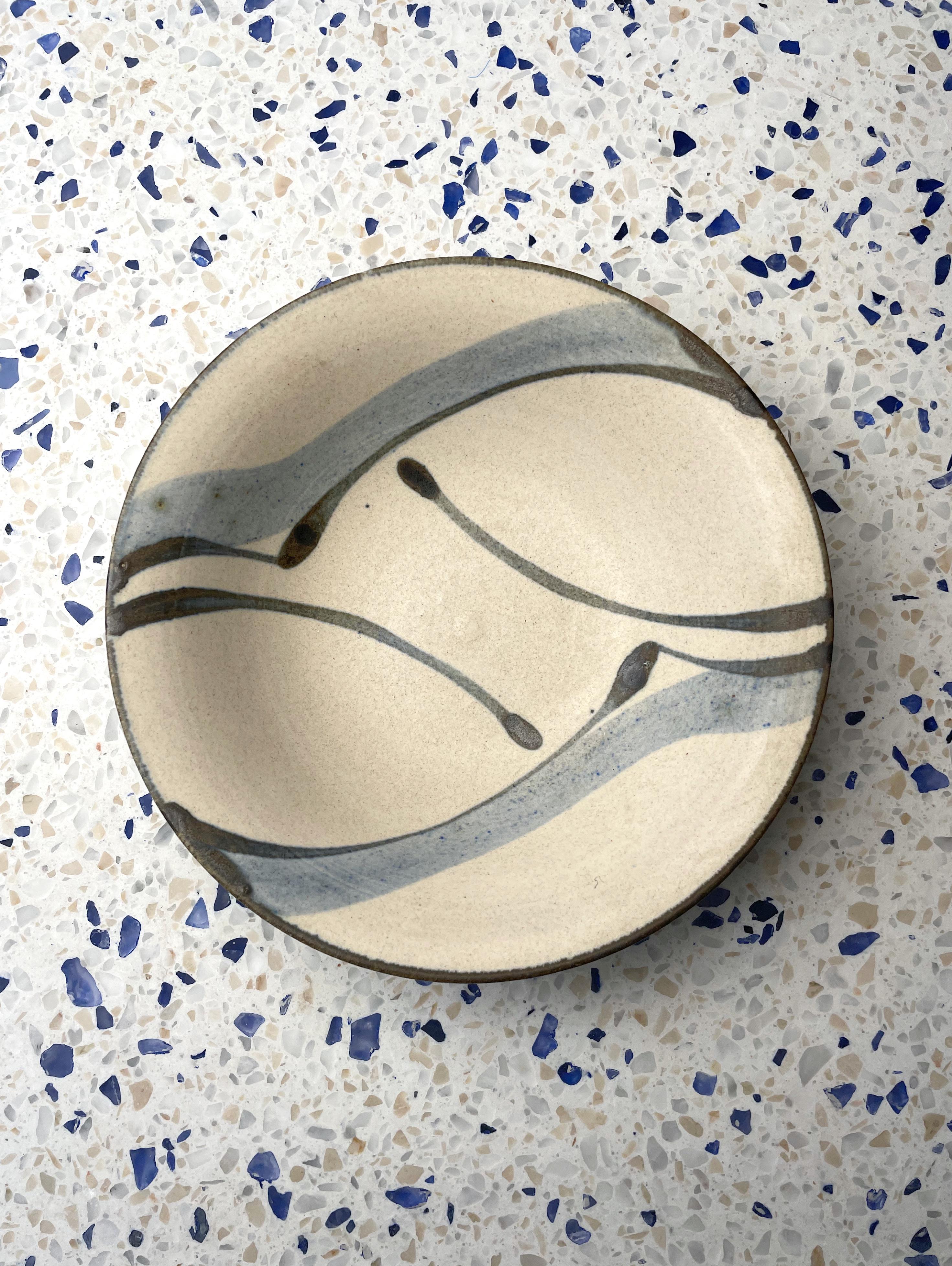 Bol en céramique danois du milieu du siècle, fait à la main, avec un décor organique tourbillonnant peint en bleu poussière et gris anthracite sur une base de couleur sable. Fabriqué par Kähler dans la ville de Townes dans les années 1970. Signé et