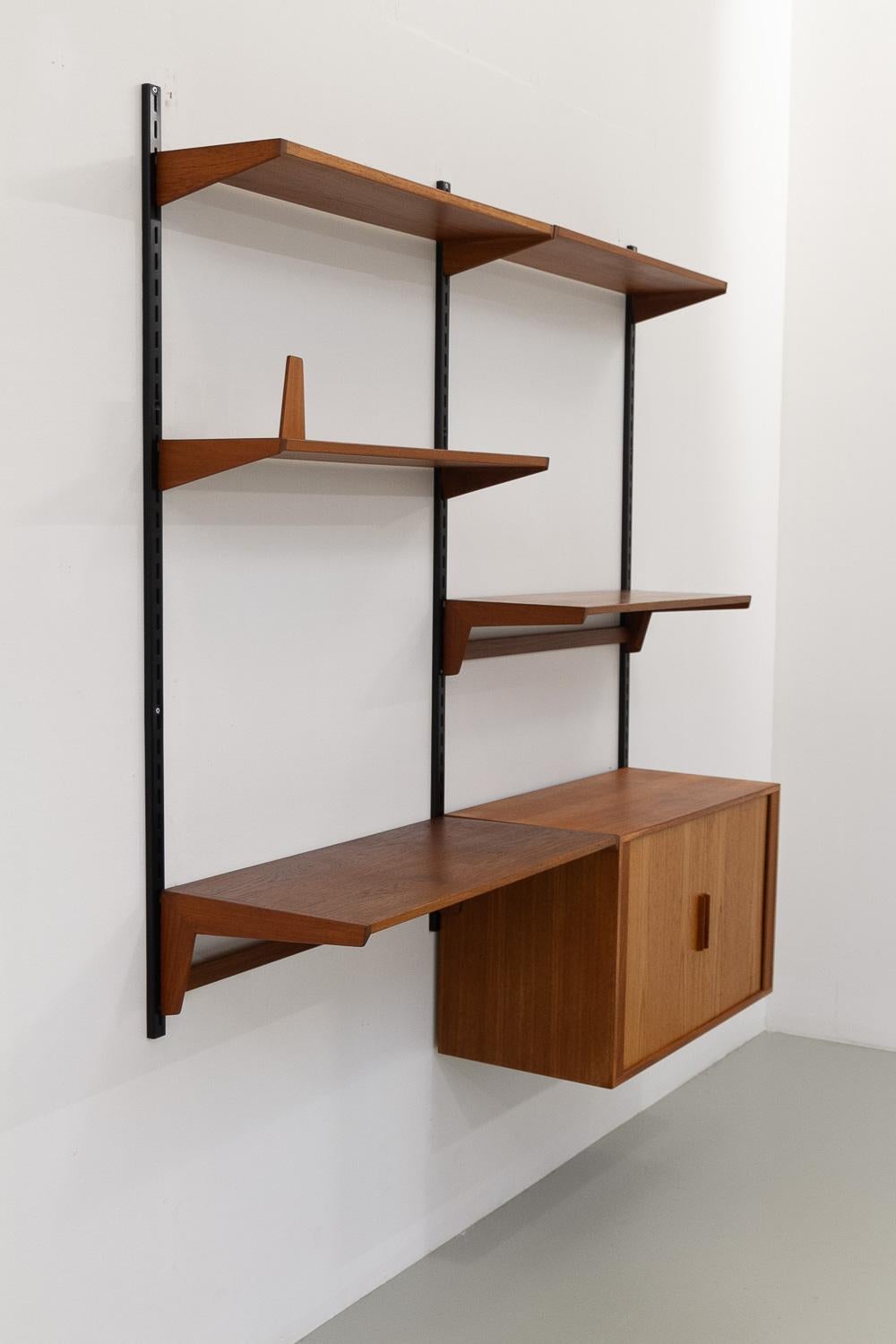 Dänische modulare Teakholz-Hängeschrankwand von Kai Kristiansen für Feldballes Møbelfabrik, Dänemark, 1960er Jahre
Modulares 2-Fach-Regalsystem Modell FM Reolsystem. 

Dieses Set besteht aus:

3 schwarze Stahllatten 150 cm.
1 Schrank, Rolltüren, 2