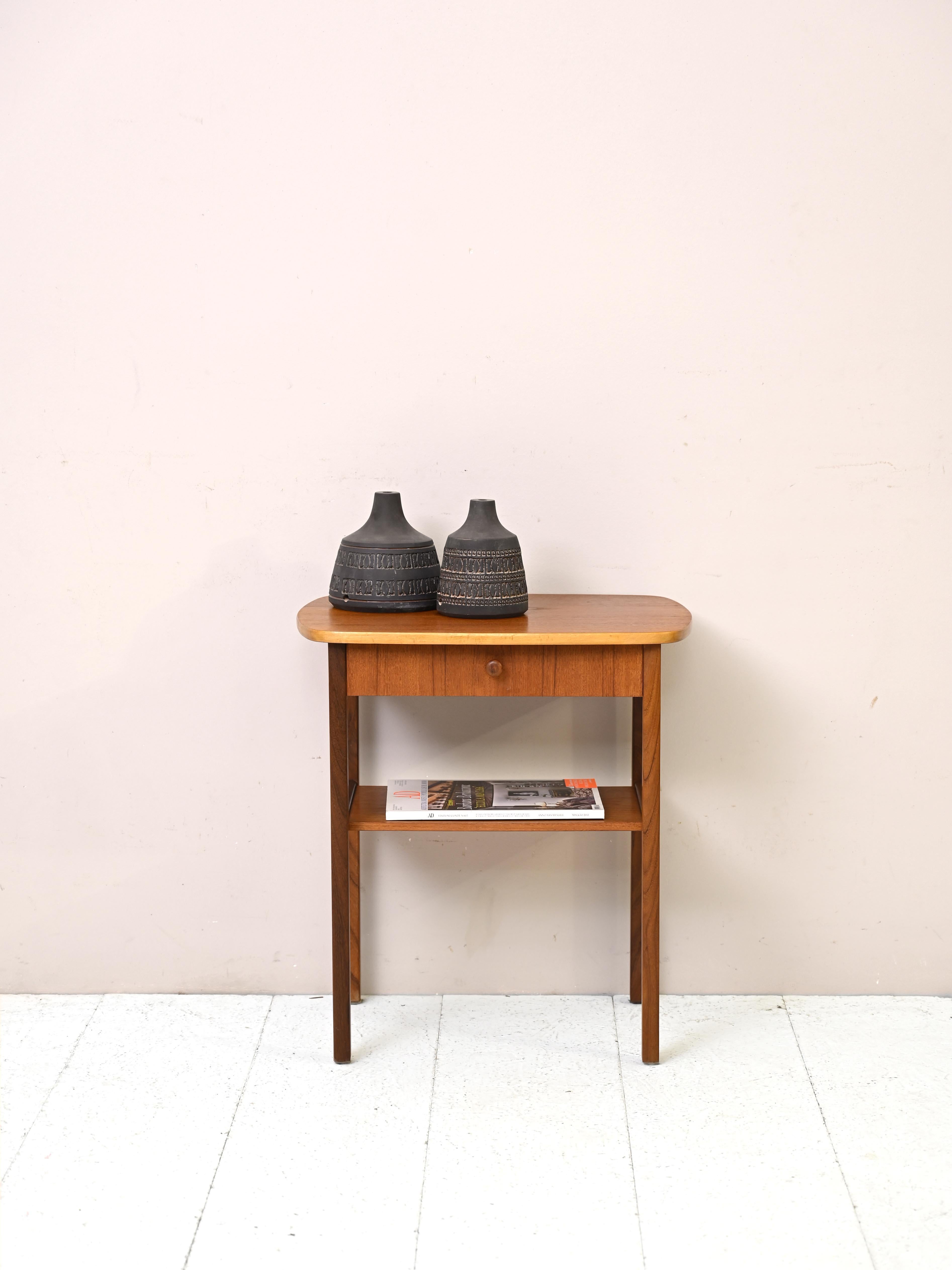 Scandinavian original 1960s nightstand.

This modern-flavored piece of furniture is distinguished by the distinctive oval shape of the drawer. The curved lines are also found in the golden metal handle and the top with rounded edges.
An original