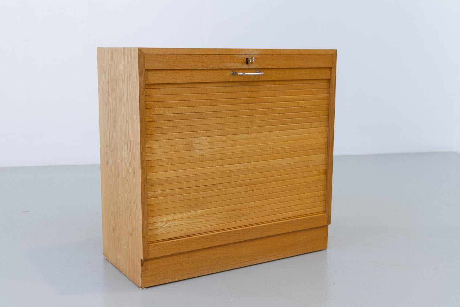 Dänischer Vintage-Schrank aus Eiche mit Tambour-Tür, 1960er Jahre.

Dänischer Mid-Century Modern Aktenschrank in Eiche mit vertikaler Rolltür. Im Inneren befindet sich ein Fach mit sechs Schubladen aus massiver Buche. Die Schubladen haben noch die
