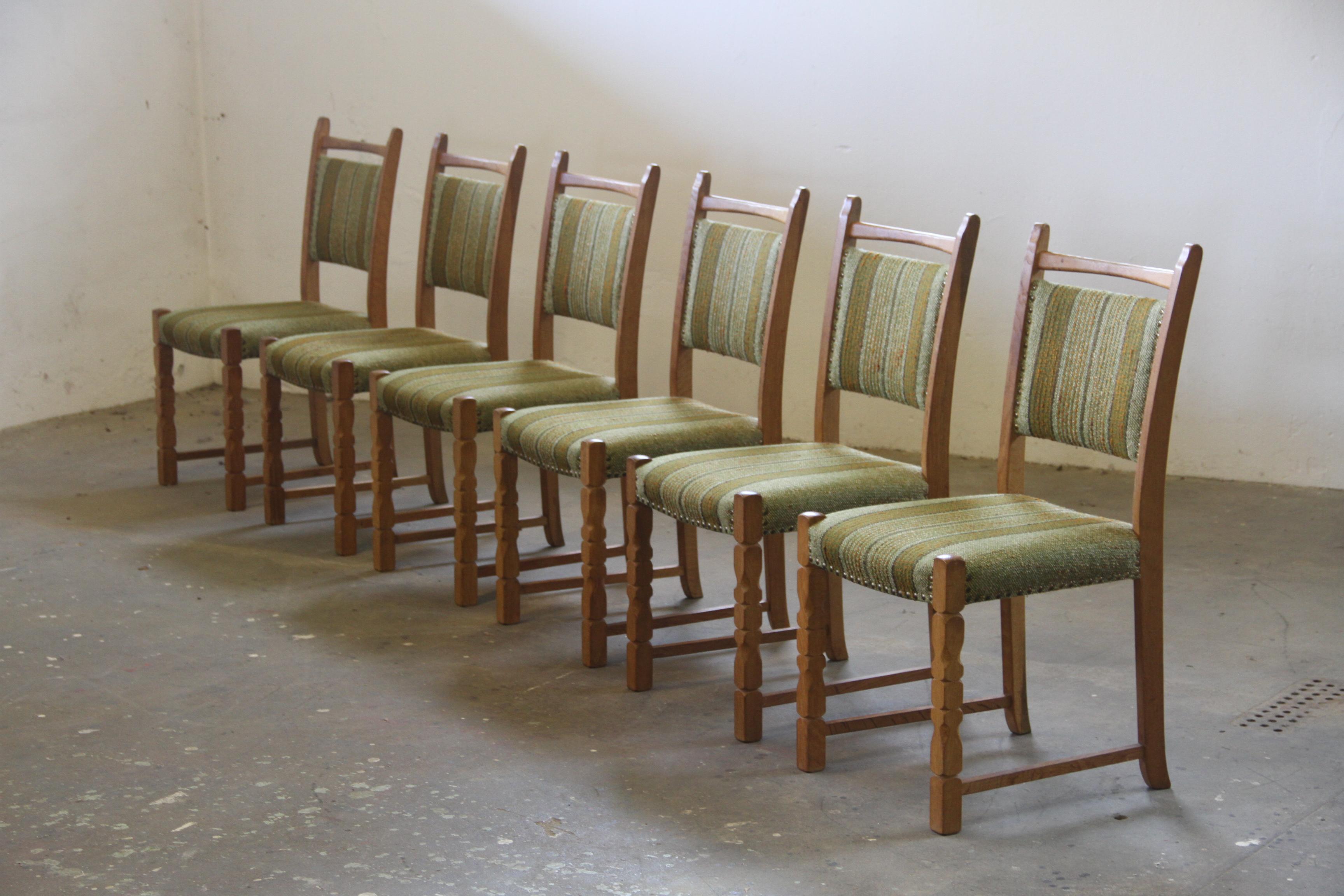 Un set di 6 sedie da pranzo vintage in oak realizzate in Danimarca negli anni '60/'70, ispirate allo stile di Henning Kjærnulf con audaci intagli brutalisti sulle gambe. Ogni sedia è solida e non presenta danni al legno, mentre il tessuto necessita