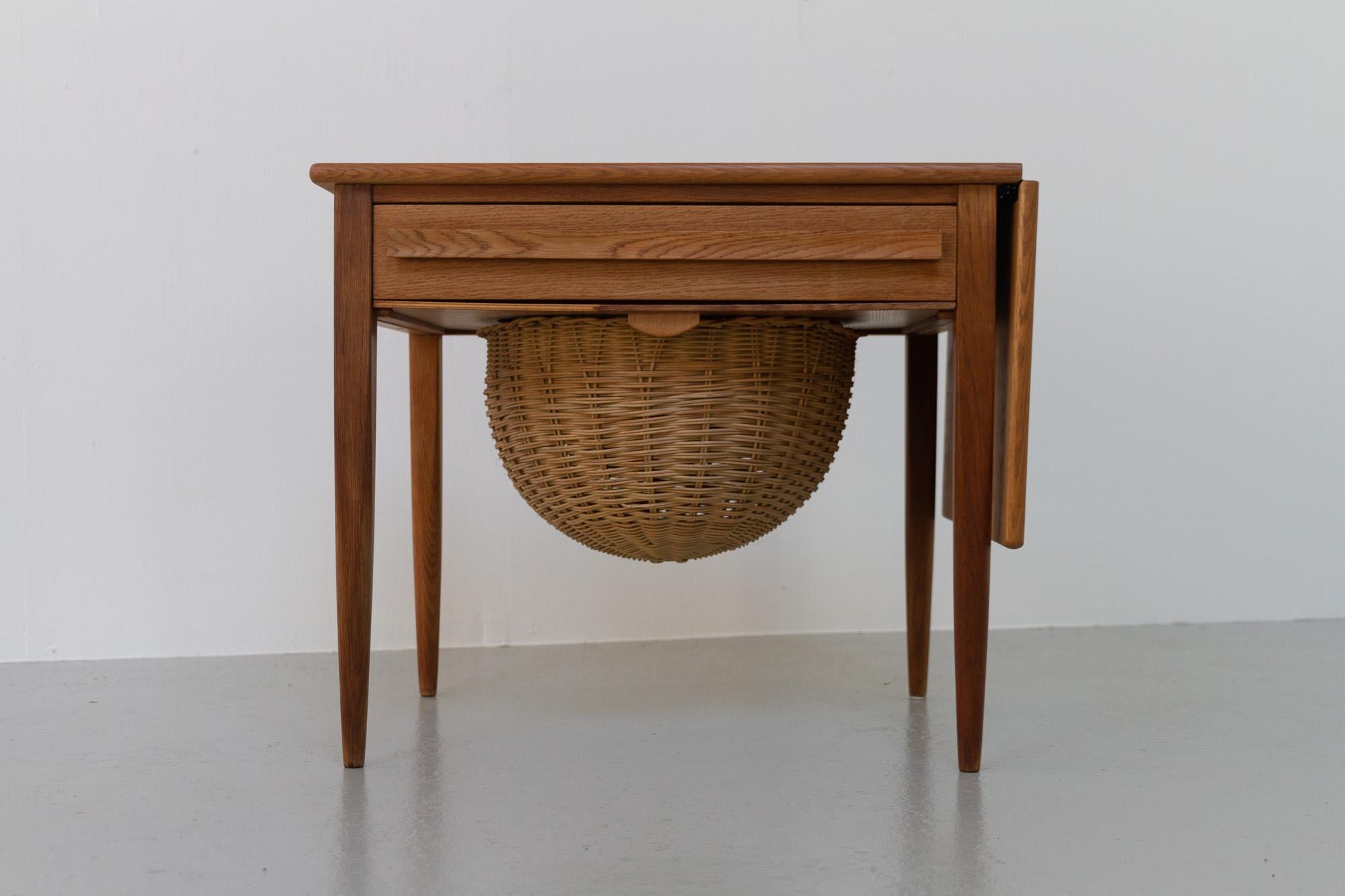 Vintage Danish Oak Sewing Table by Johannes Andersen, 1960s.

Elegant and versatile small table with drawer and wicker basket designed by Danish architect Johannes Andersen for CFC Silkeborg, Denmark in the 1960s.
The drawer features several