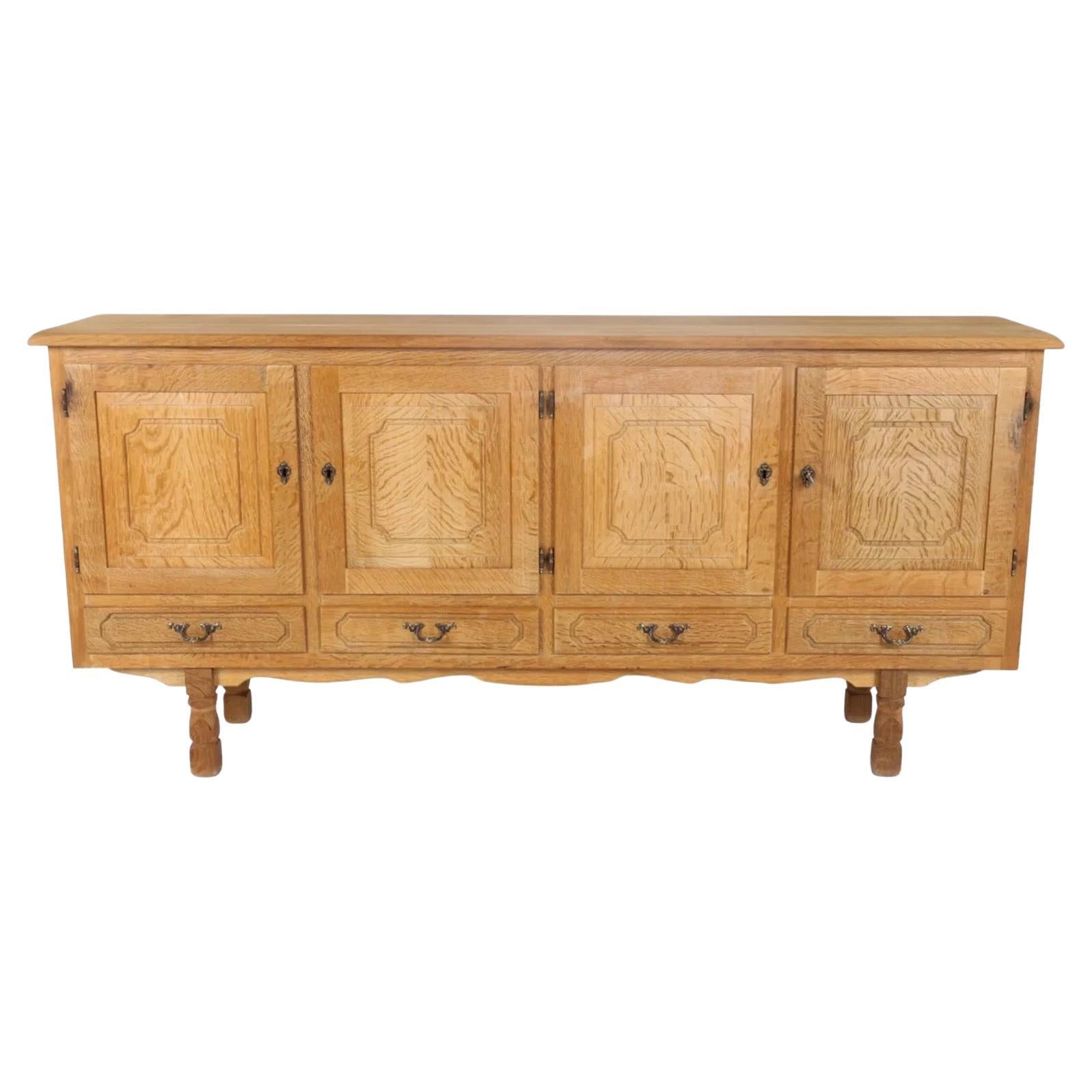A finely crafted Danish oak sideboard attributed to Henning Kjaernulf, known for his sculptural designs that merge traditional craftsmanship with modern functionality. Dating to the 1960s, this piece showcases quartered oak veneer panels with