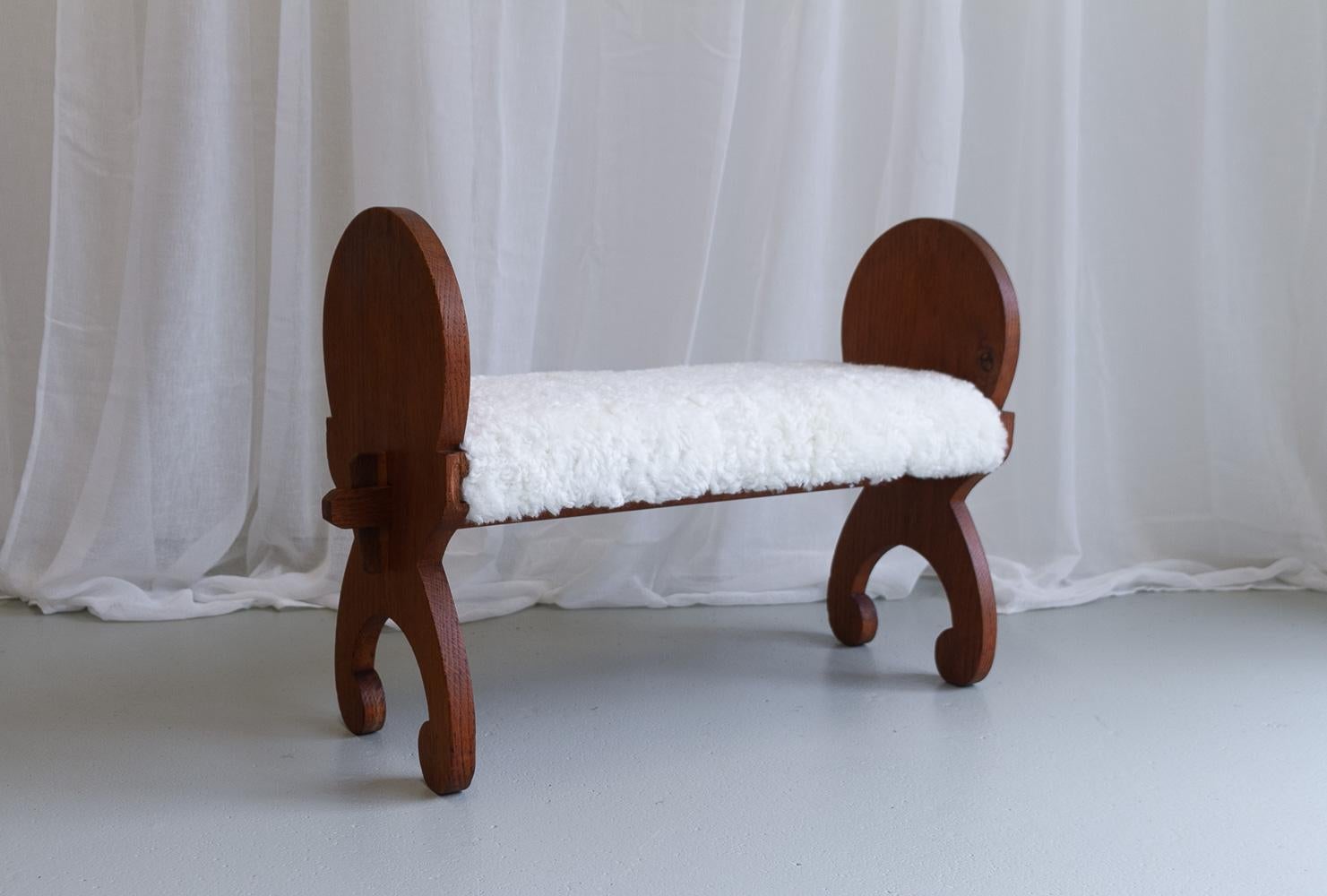 Vintage Danish Oak Stool with Lambskin, ca 1900s.
Antique stool in solid oak from Denmark early 20th century. Inspired by the medieval or viking era. Probably used as a footstool or a childrens bench. 

Seat has been re-upholstered with new white