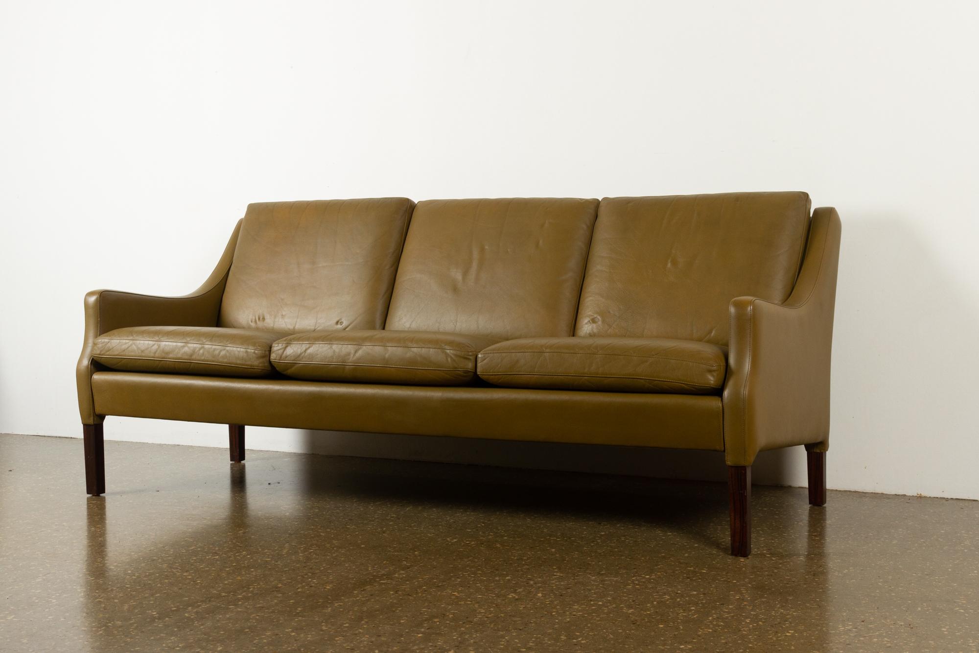Vintage Danish olive green leather sofa, 1960s
Very stylish Mid-Century Modern Danish three-seat couch with original stunning olive green leather upholstery. Beautifully curved armrests. Comfortable with thick and soft seat cushions, leather is