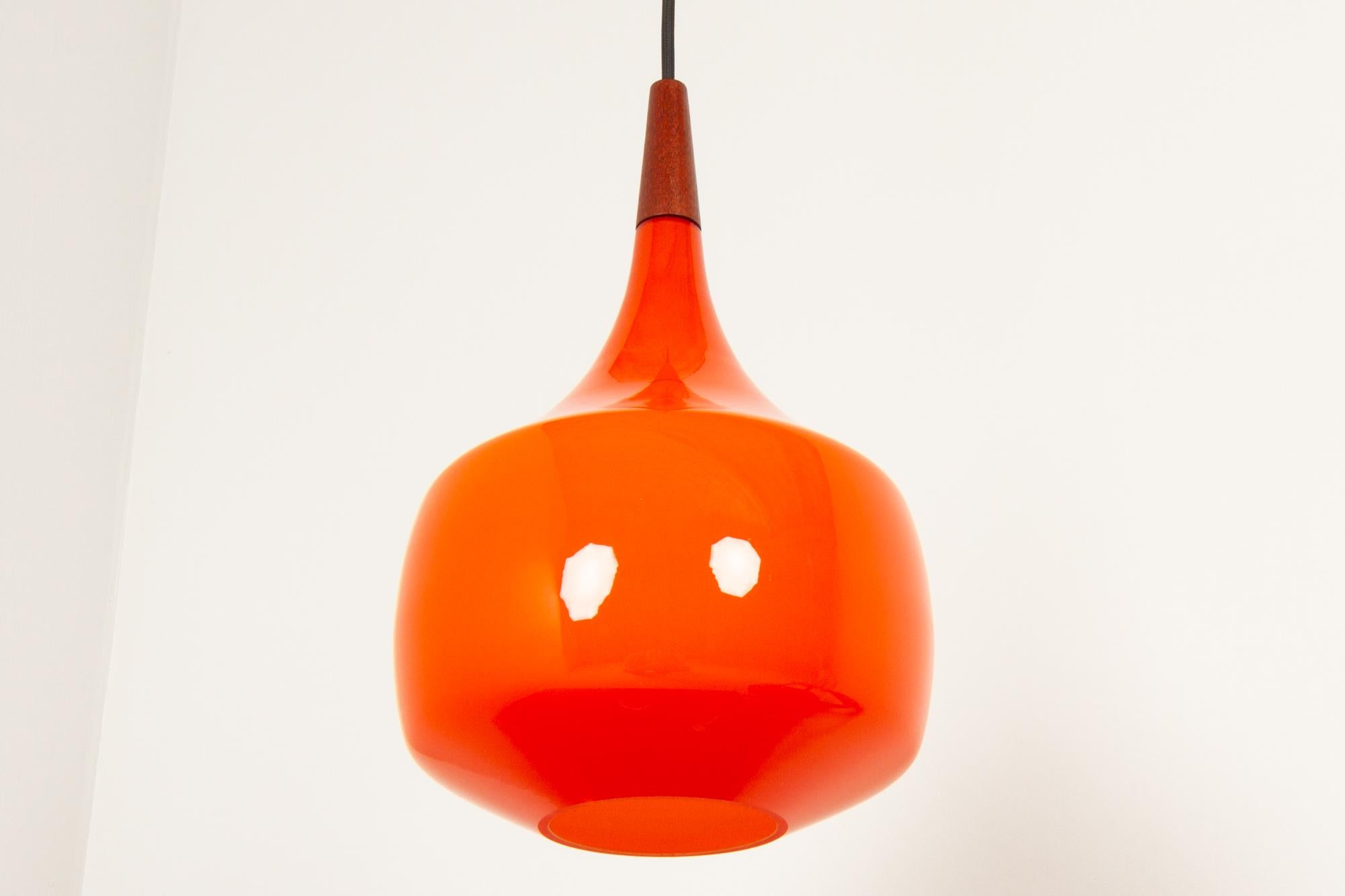Vintage Danish orange glass pendant by Holmegaard, 1960s.
Danish modern ceiling lamp in opaline glass made by Danish glass works Holmegaard. This is the rare version in a warm and vivid orange color with a top in solid teak.
Marked 