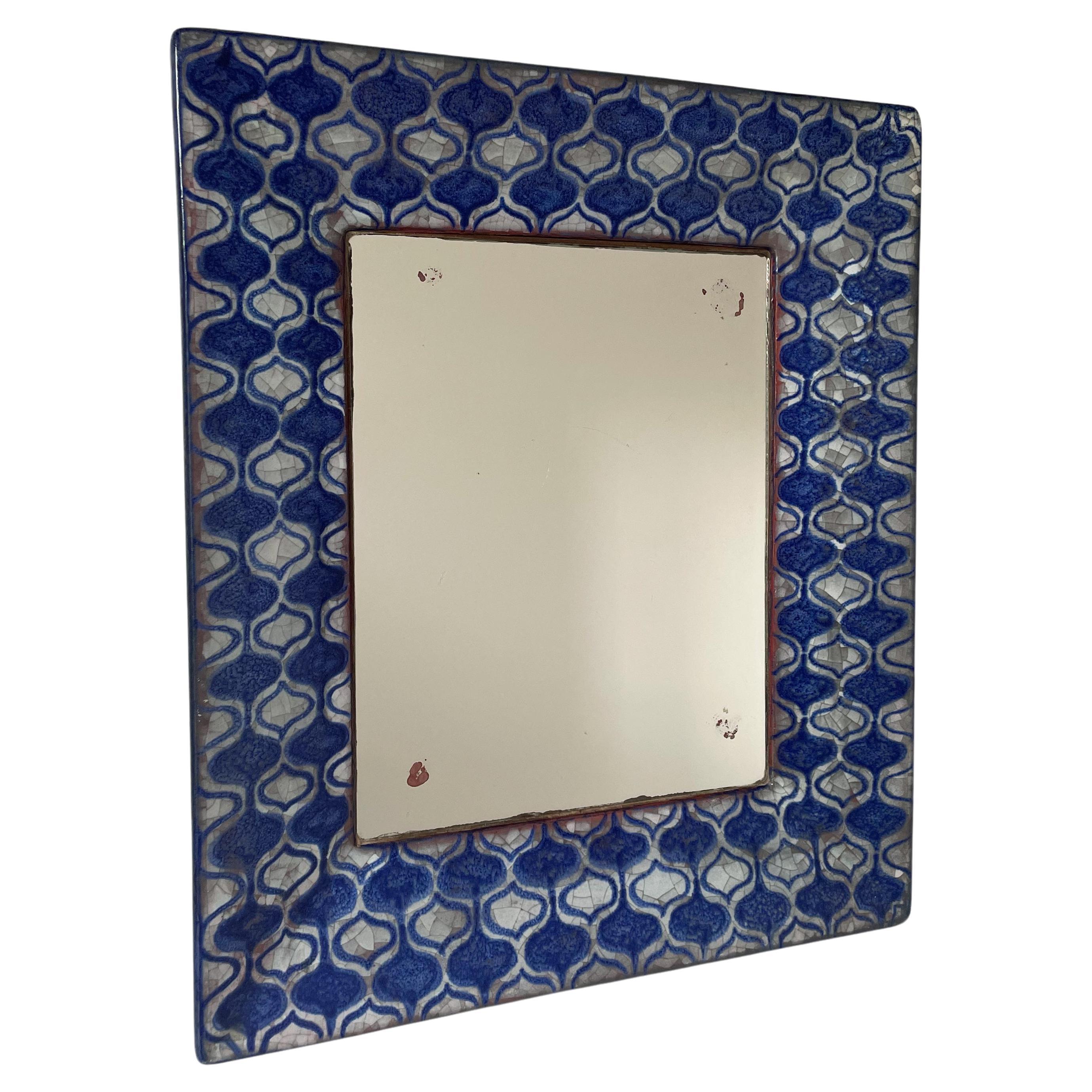 Danish ceramic wall mirror decorated by hand and designed by Marianne Starck for Michael Andersen & Son in the 1960s. Solid, thick ceramic frame with navy blue and light grey persia crackle glaze hand painted in a graphic, stylized pattern with soft