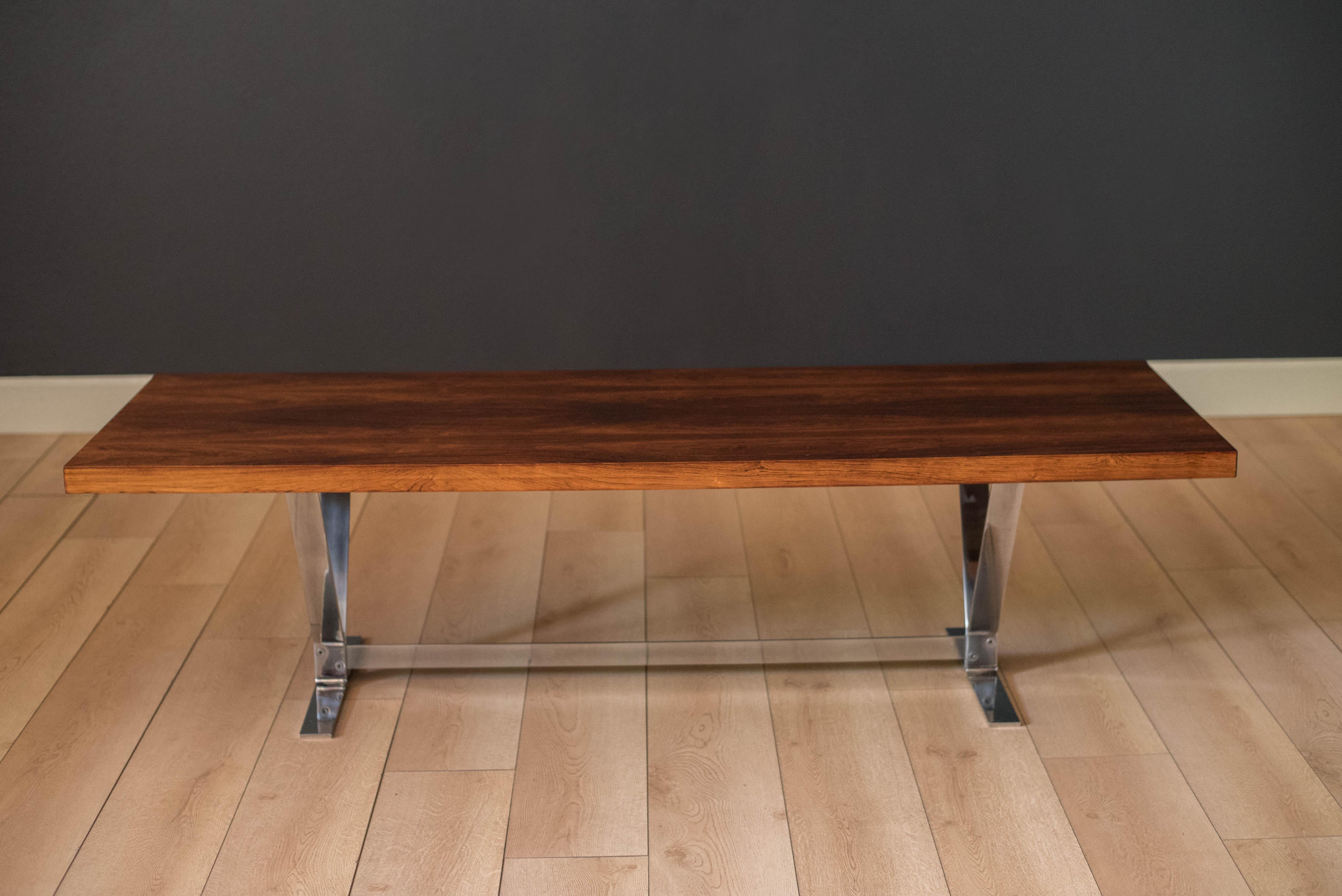 Classic Mid-Century Modern coffee table in rosewood by Georg Thams for Vejen Polstermøbelfabrik circa 1970s. This piece features a long and sleek rectangular tabletop supported by a heavy sculptural polished chrome base. Complements vintage or