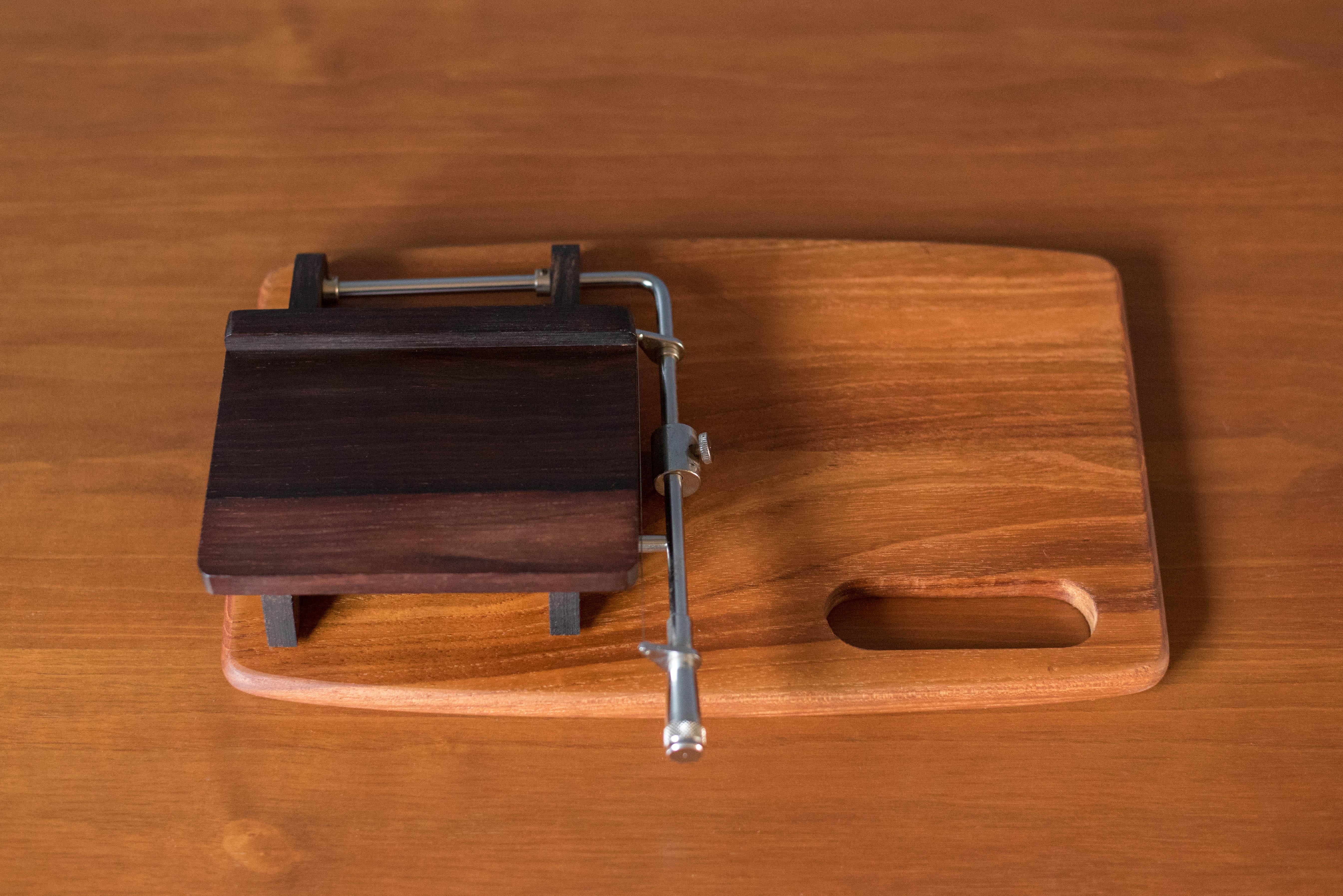 Mid century modern 'Oste-Mik' cheese slicing board manufactured by Andreas Hansen, circa 1960's. This unique piece is made with a solid teak serving tray with a contrasting rosewood slicer board and metal wire cutter. Great for entertaining and