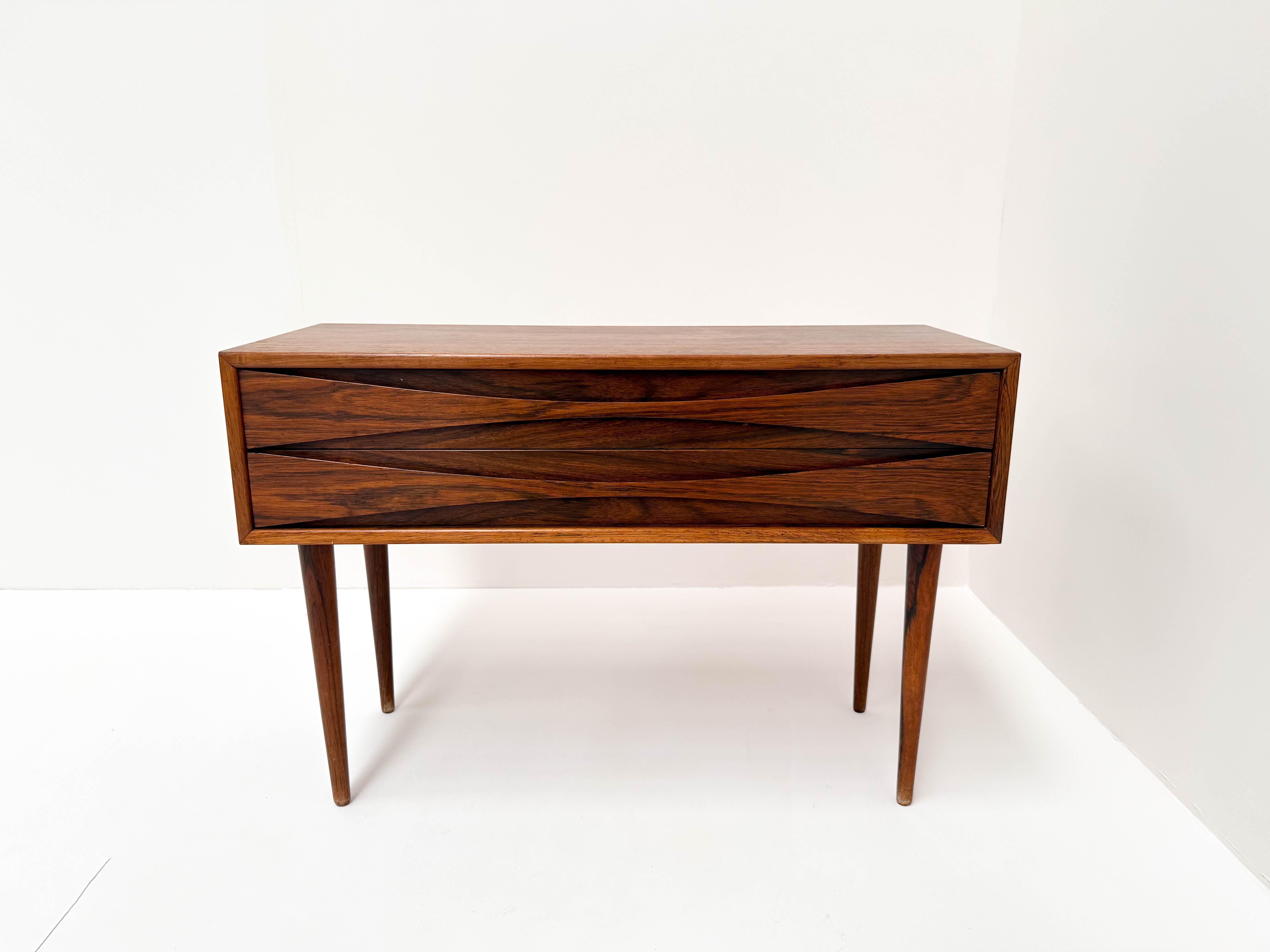 Add a touch of Danish mid-century modern elegance to your home with this stunning rosewood bedside chest, designed by Niels Clausen for NC Møbler in the 1960s. Crafted from rich, beautifully grained rosewood, this rare piece embodies Scandinavian