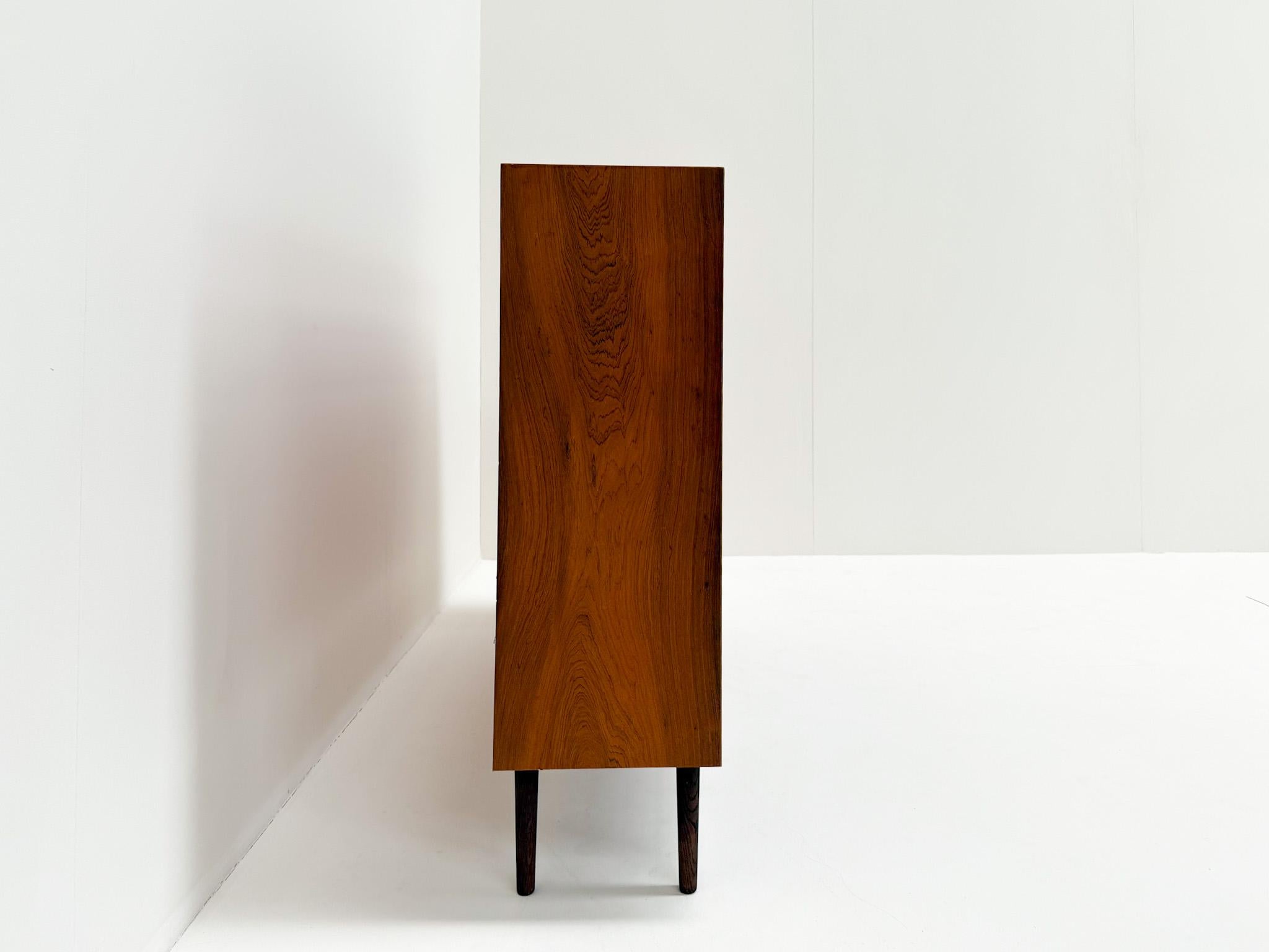Magnifique bibliothèque danoise vintage en bois de rose, présentant un grain de bois époustouflant et des lignes épurées et minimalistes. Conçue dans le style moderne du milieu du siècle, elle offre quatre étagères réglables, parfaites pour les