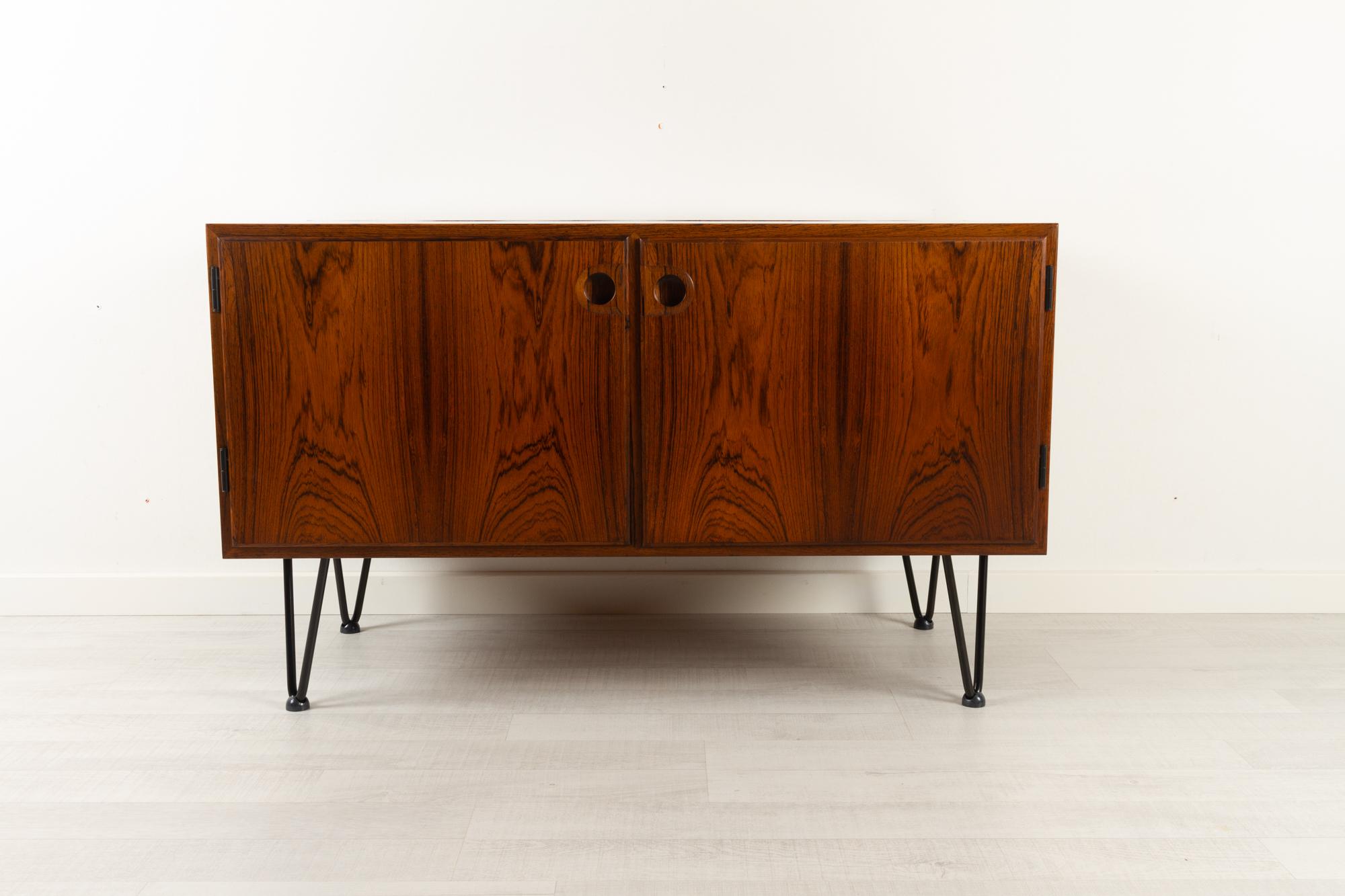 Vintage Danish rosewood cabinet 1960s
Mid-Century Modern small sideboard in Rosewood made in Denmark. Two compartments with hinged doors. Inside with two height adjustable shelves. Very vivid and expressive Rosewood grain. Sculpted handles in solid