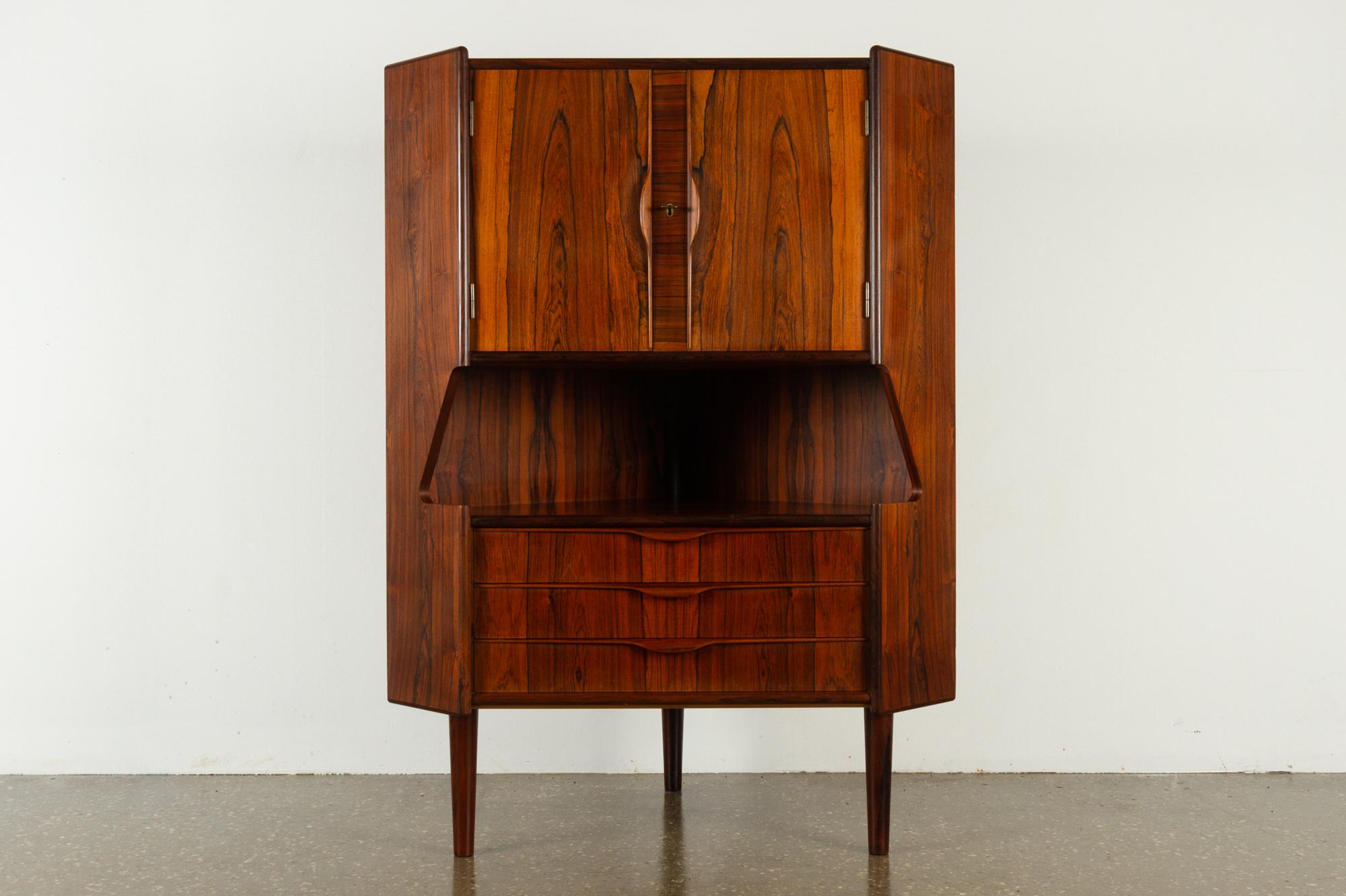Vintage Danish rosewood corner cabinet, 1960s
Mid-Century Modern corner cabinet with bar unit and drawers. Cabinet behind double doors with lock and key. Inside decorated mirror and curved shelf. Amble space for glasses and bottles. Underneath is a