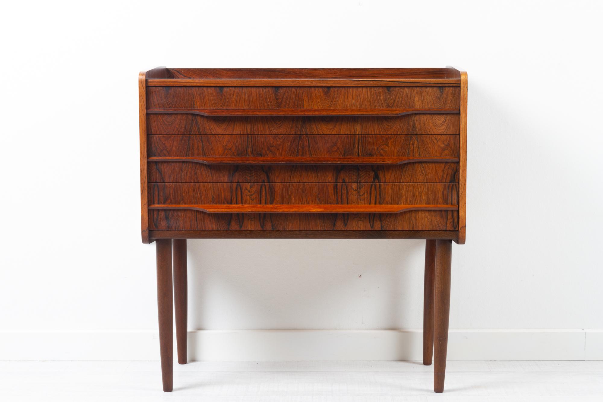Vintage Danish rosewood dresser 1960s
Small Danish Mid-Century Modern dresser in beautiful expressive Rosewood veneer. 
Three wide drawers with long sculpted pulls in solid Rosewood. Drawers has dovetail joints and are lined with green felt.