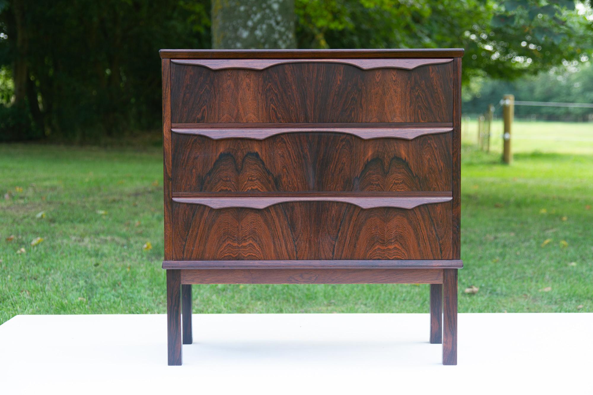 Vintage Danish Rosewood Dresser 1960s
Elegant Danish Mid-century Scandinavian Modern chest of drawers in Rosewood. Three wide drawers with dovetail joints and sculpted pulls in solid Rosewood. 
Beautiful and expressive Rosewood veneer with distinct