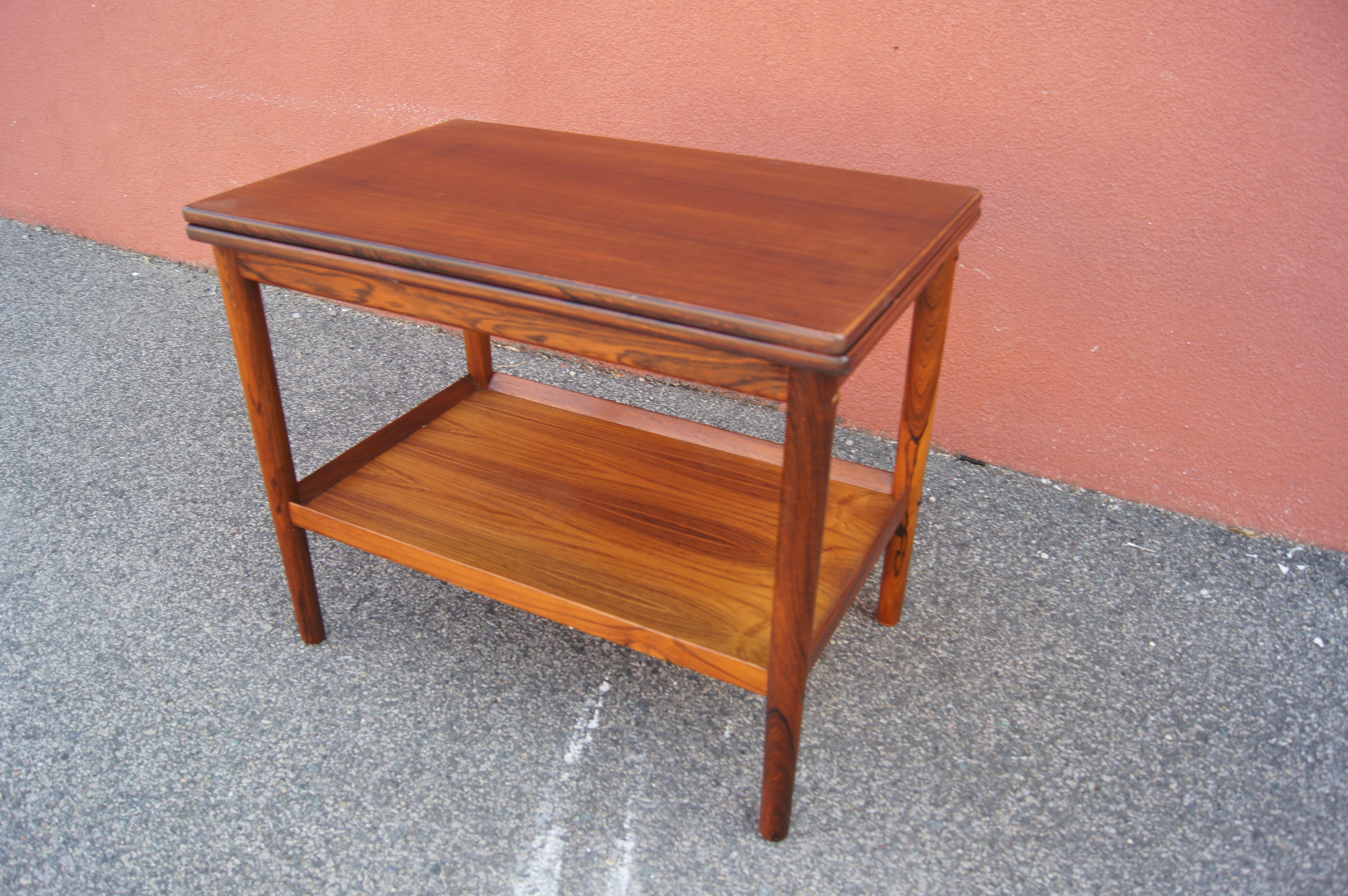 This clever midcentury Danish table has a rosewood frame with two tiers, a lower rimmed shelf and a top that expands the surface area with a twist and flip.
 
When the flip top is fully open, the table top measures 35.75 inches.
 