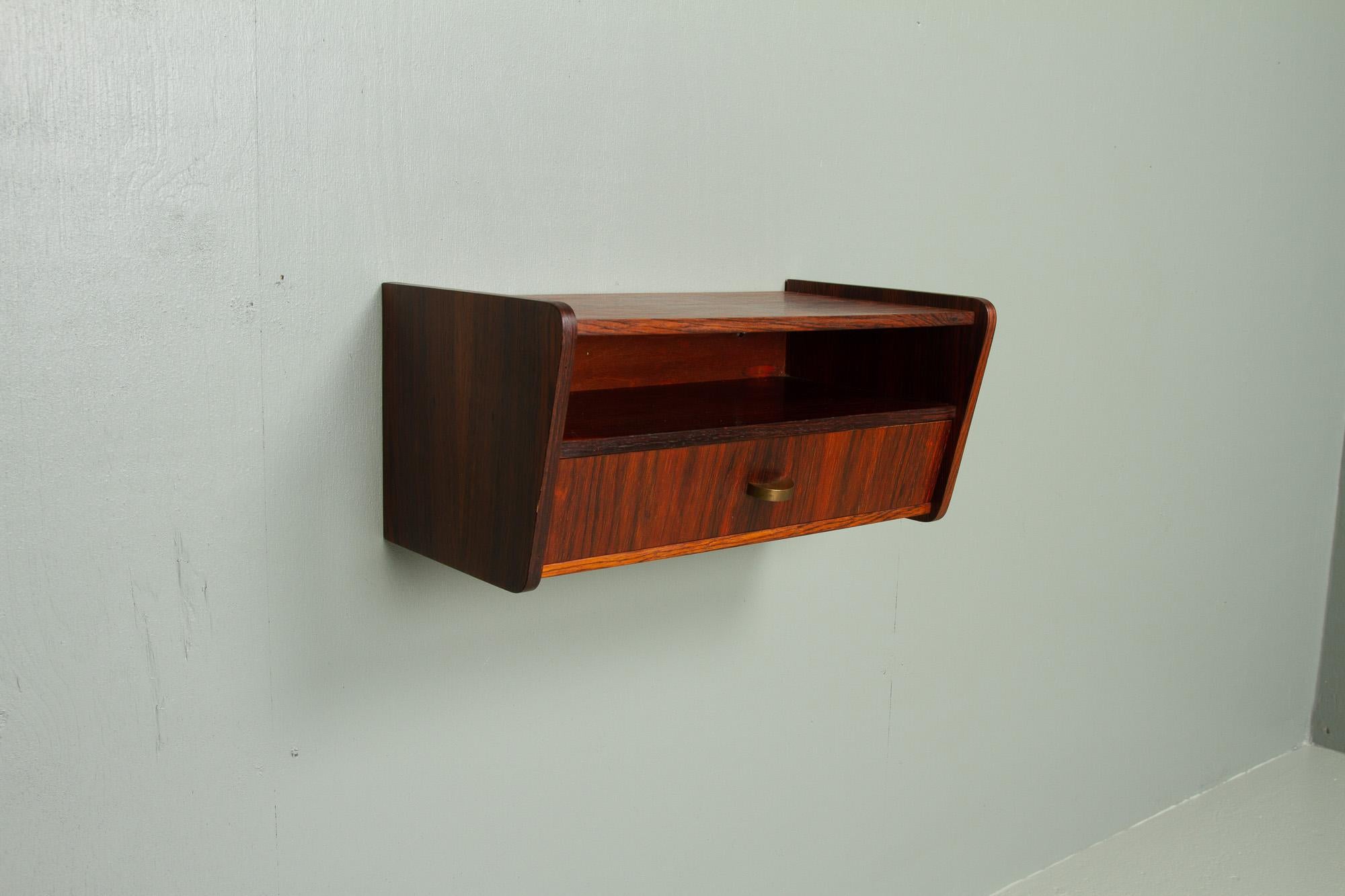 Vintage Danish rosewood floating shelf, 1960s.
Mid-Century Modern wall mounted bedside table/nightstand/wall console made in Denmark in the 1960s. Featuring an open shelf and a drawer with a brass pull.
Beautiful and expressive Rosewood