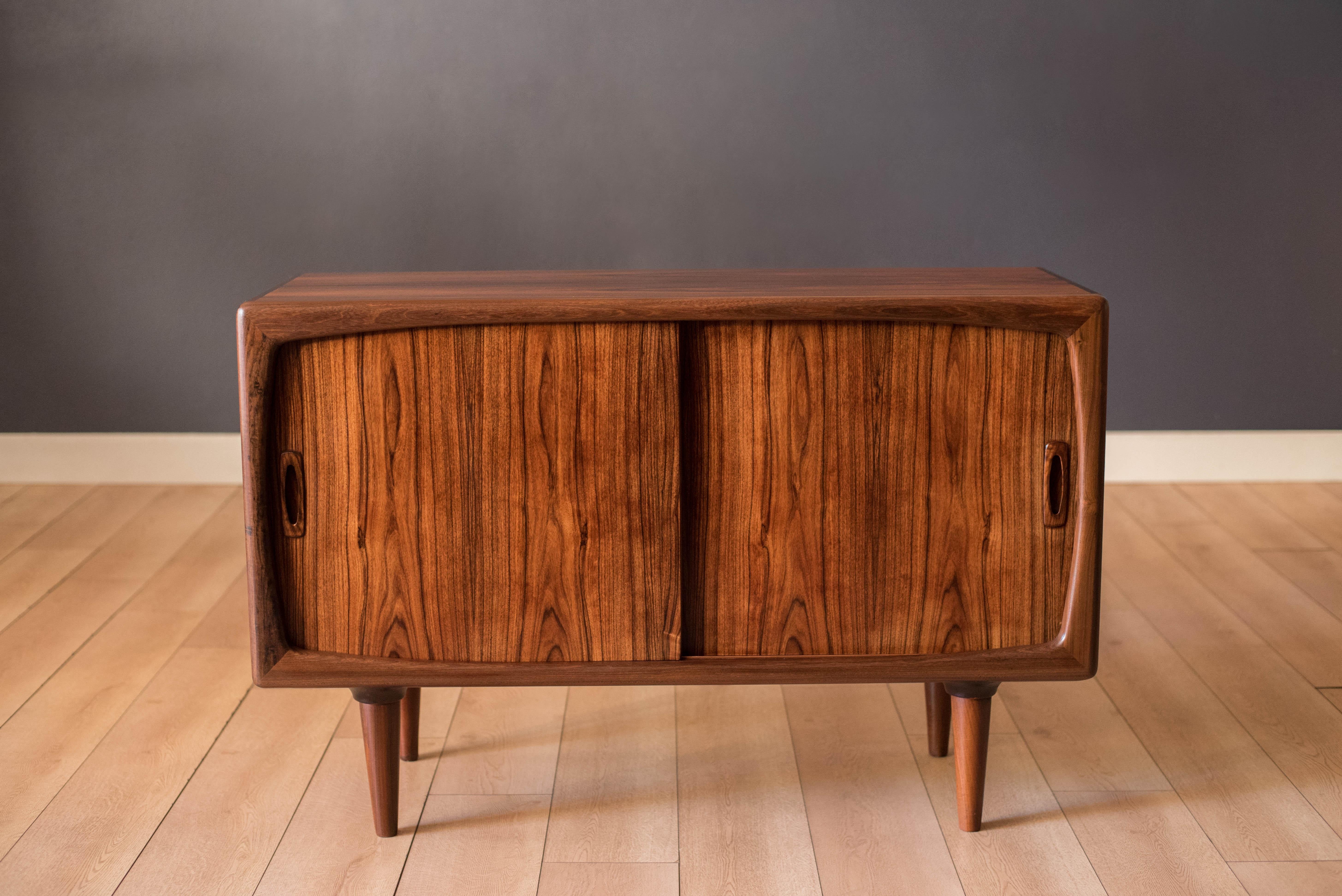 Mid-Century Modern credenza sideboard buffet by H.P. Hansen in rosewood, circa 1960s. Features solid sculpted pulls and space saving sliding doors that offer hidden storage with adjustable shelving. This versatile piece can be used as a media