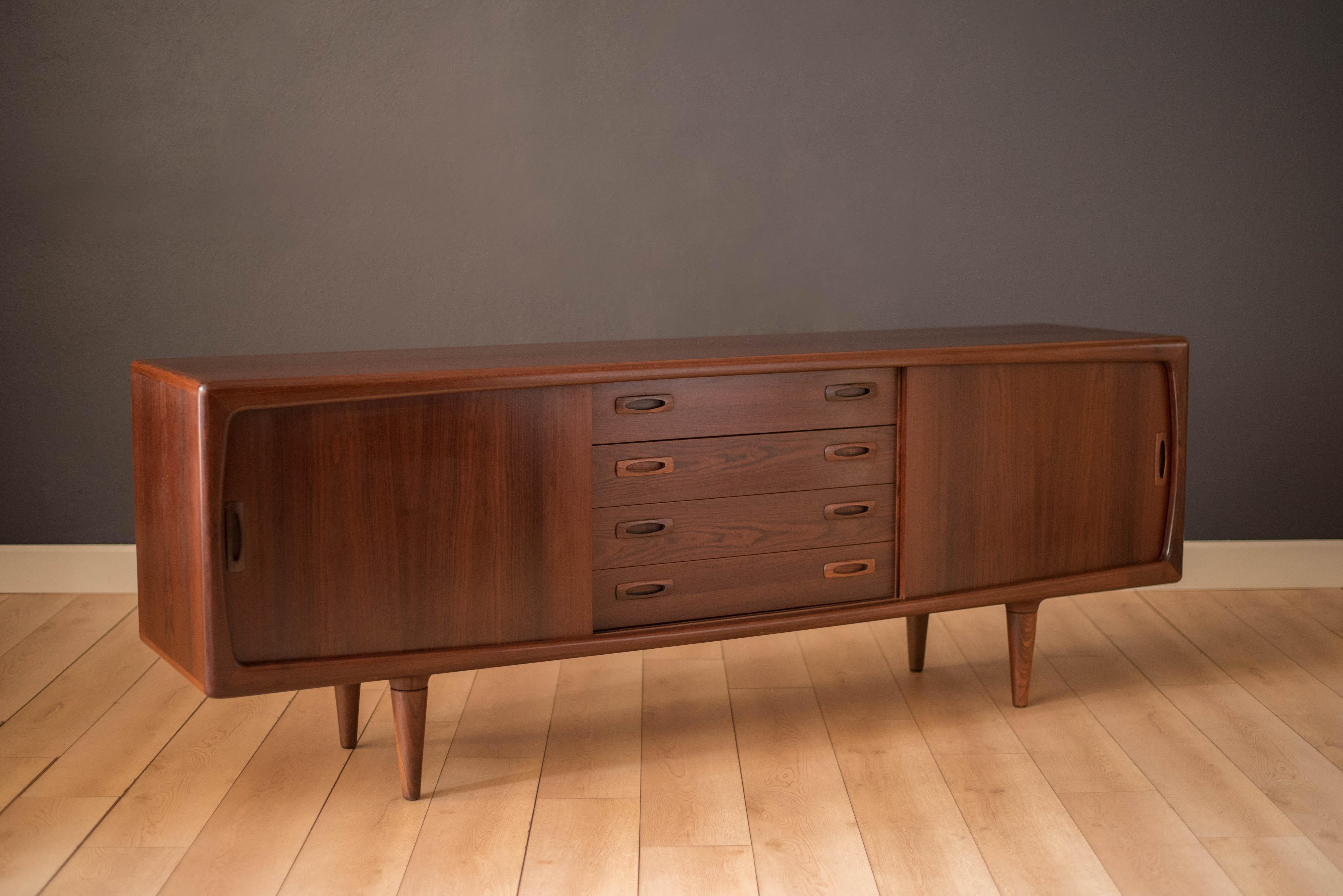 Mid-Century Modern credenza by H.P. Hansen in rosewood, circa 1960s. This showcase piece features four storage dovetailed drawers with sculpted handles and two open cabinets with adjustable shelving concealed by sliding doors.

 