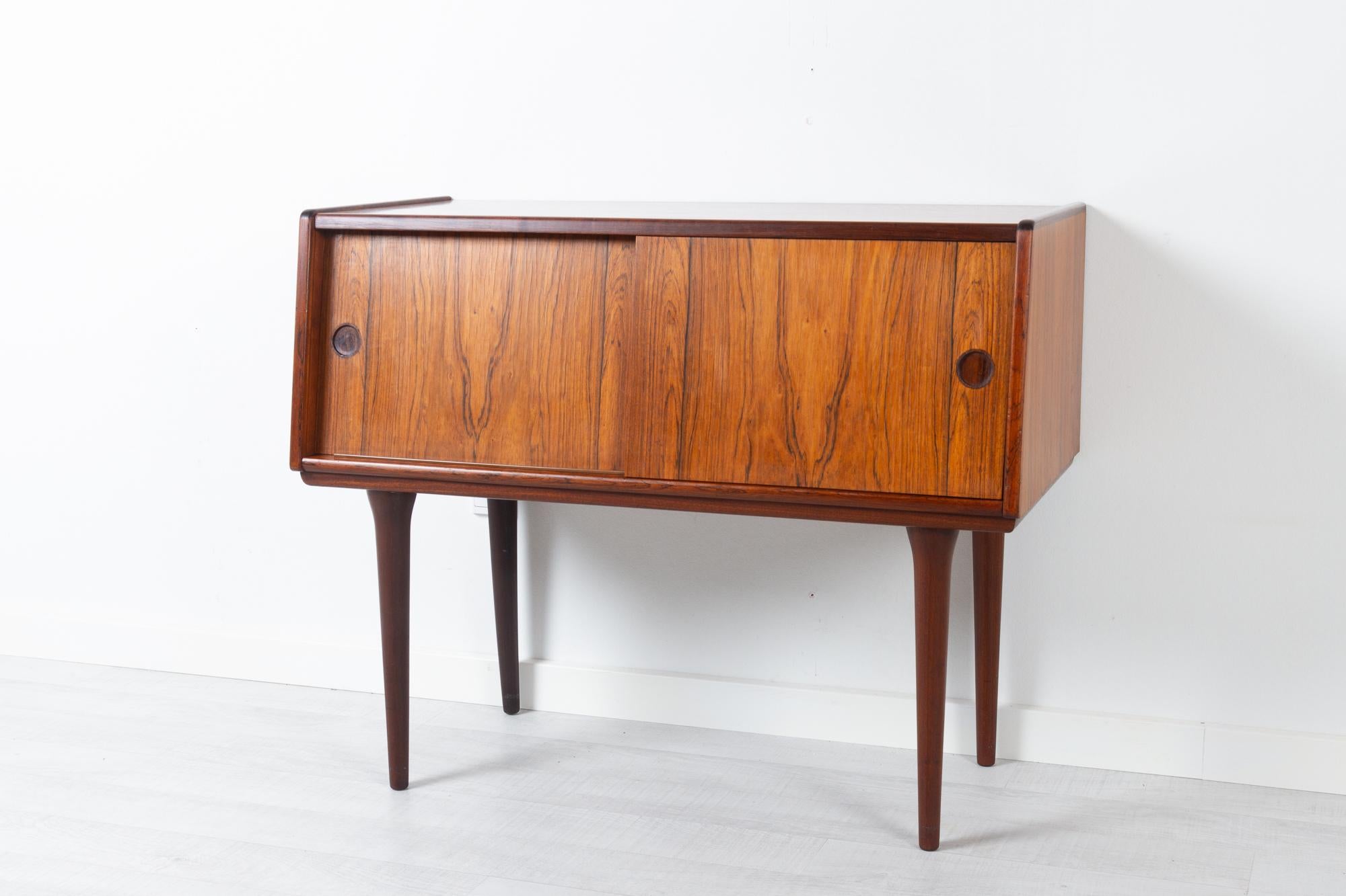 Vintage Danish rosewood sideboard 1960s
Small Danish Mid-Century Modern sideboard with sloping front and double sliding doors. Inside divided into two compartments, one with a fixed shelf.
Cabinet in Rosewood veneer. Tall round tapered legs in