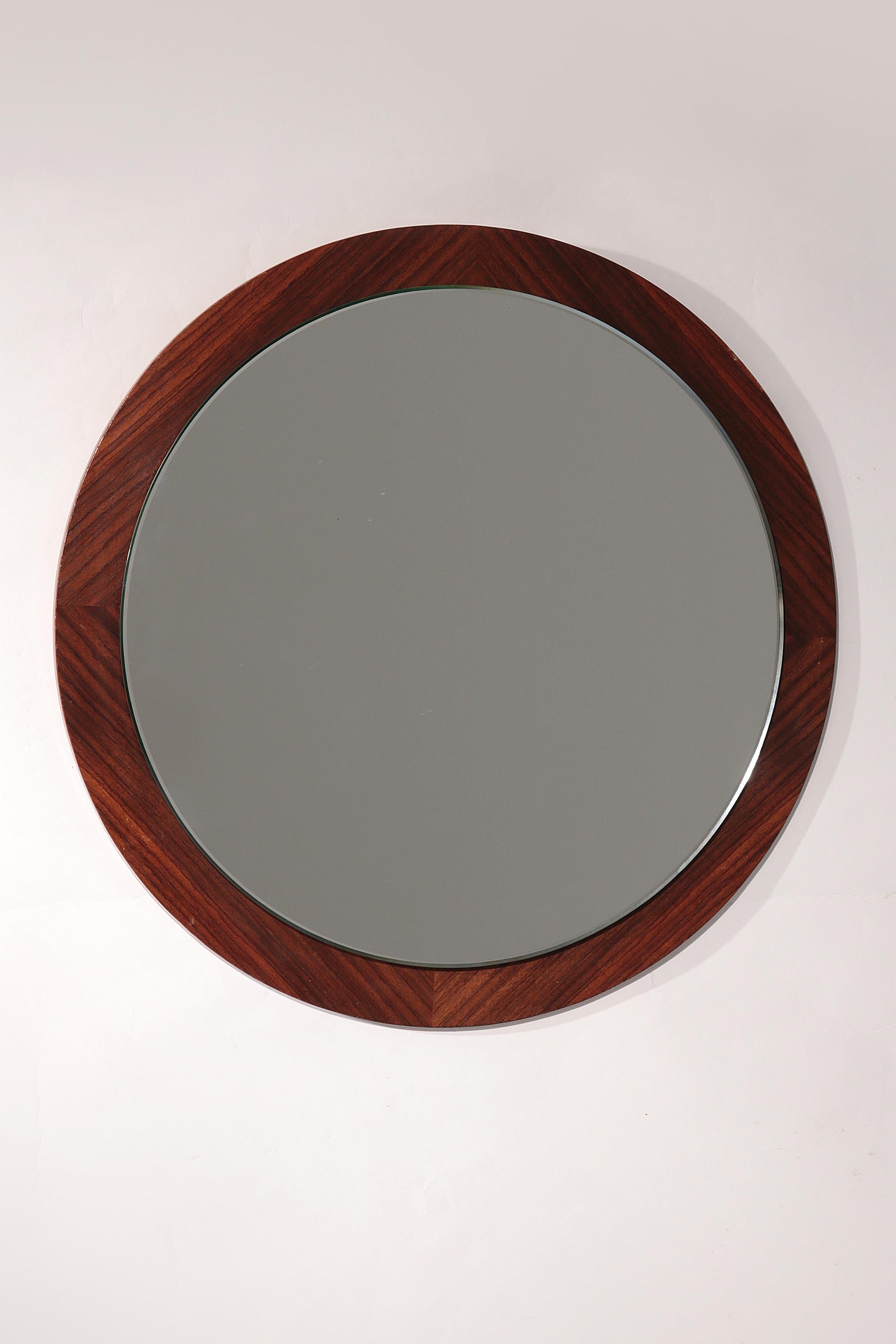 

Questo grande specchio circolare vintage da parete incarna l'essenza del design moderno danese, prodotto tra gli anni '60 e '70. Lo specchio presenta una cornice in impiallacciatura di palissandro finemente lavorata, che mette in risalto i toni