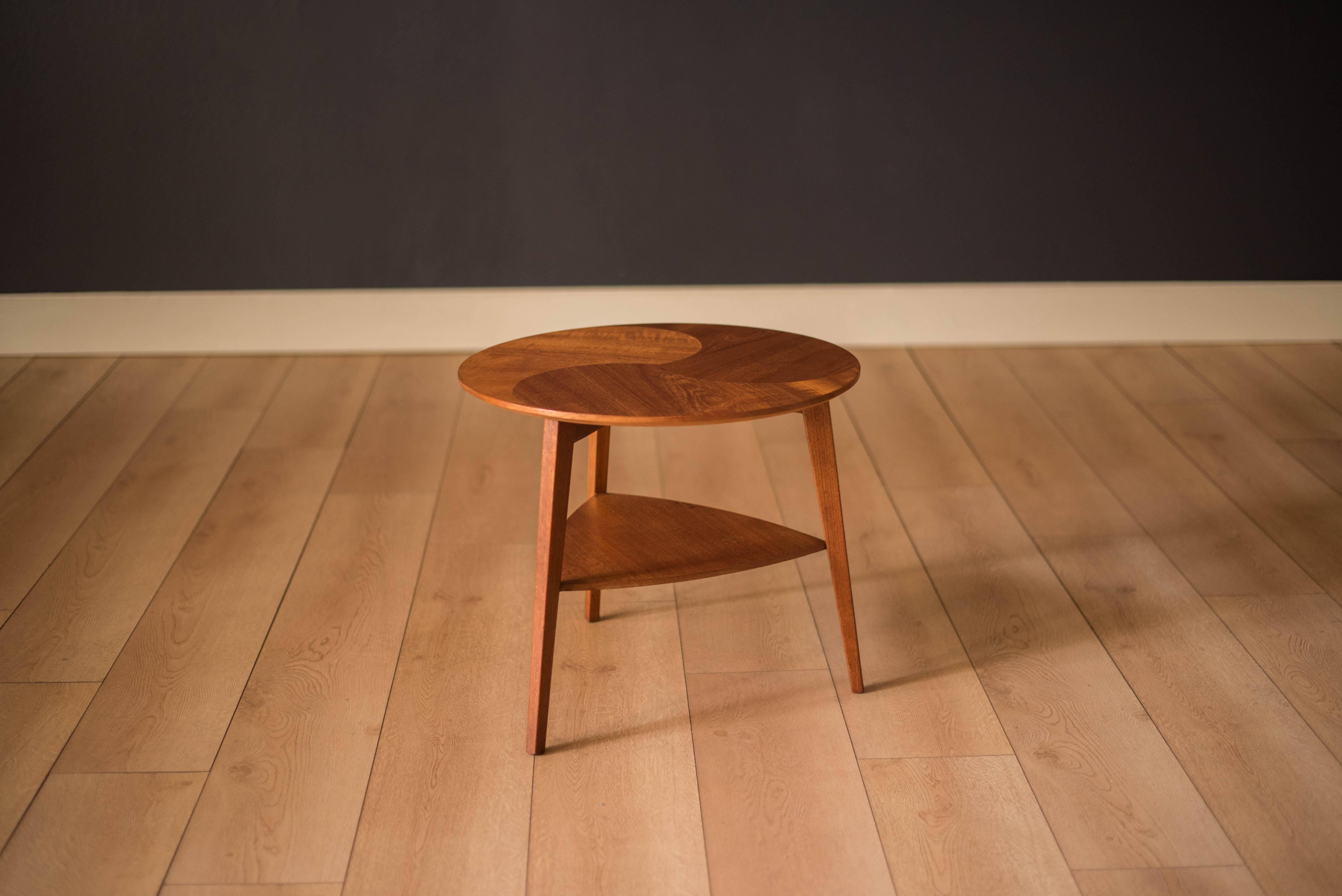 Mid-Century Modern round occasional side table manufactured by Mobelintarsia, Denmark. This two-tier piece features a contrasting teak round top with a lower triangular shelf.