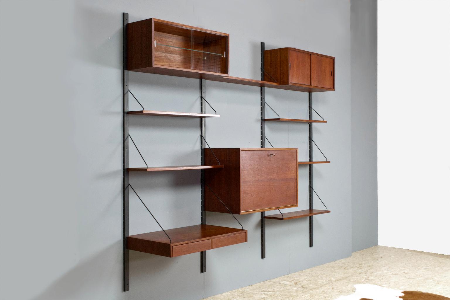 Adjustable, modular Royal wall mounted shelving system in teak, designed in 1948 by Poul Cadovius (1911-2011). This Royal wall unit is adjustable, all elements can be placed in various positions in the black wooden uprights/ brackets.

The listed