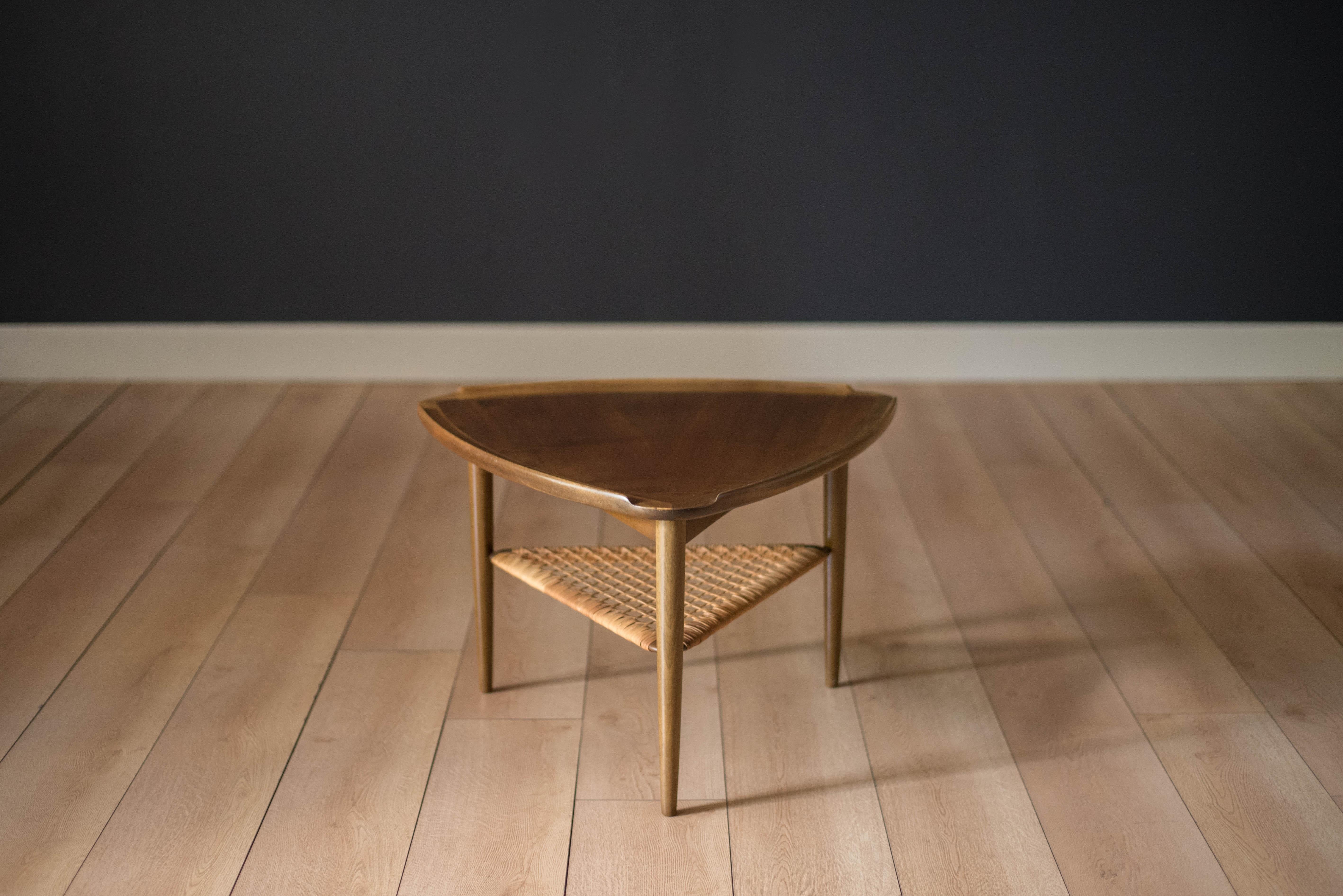 Mid Century triangular occasional table or guitar pick side table designed by Poul Jensen imported by Selig, Denmark. This piece features a unique walnut raised edge top and lower tier magazine shelf made of woven cane.



Offered by Mid Century