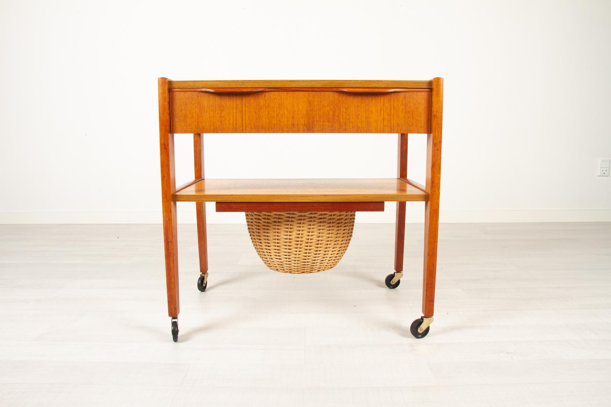 Vintage Danish sewing table, 1960s
Danish modern oak and teak sewing cart on casters. Wide drawer with sculpted double pulls. Original draw out cane basket. Ideal as a side or lamp table. 
Cleaned and polished. Some watermarks on top.