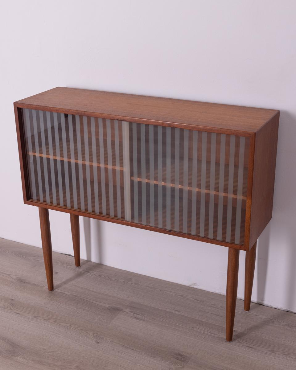 Low display cabinet, with teak wood structure and two sliding doors in striped glass, design Paul Cadovius, 1960s.

Condition: In good condition, working, may show light signs of wear.

Dimensions: Height 79 cm; Width 90cm; Depth