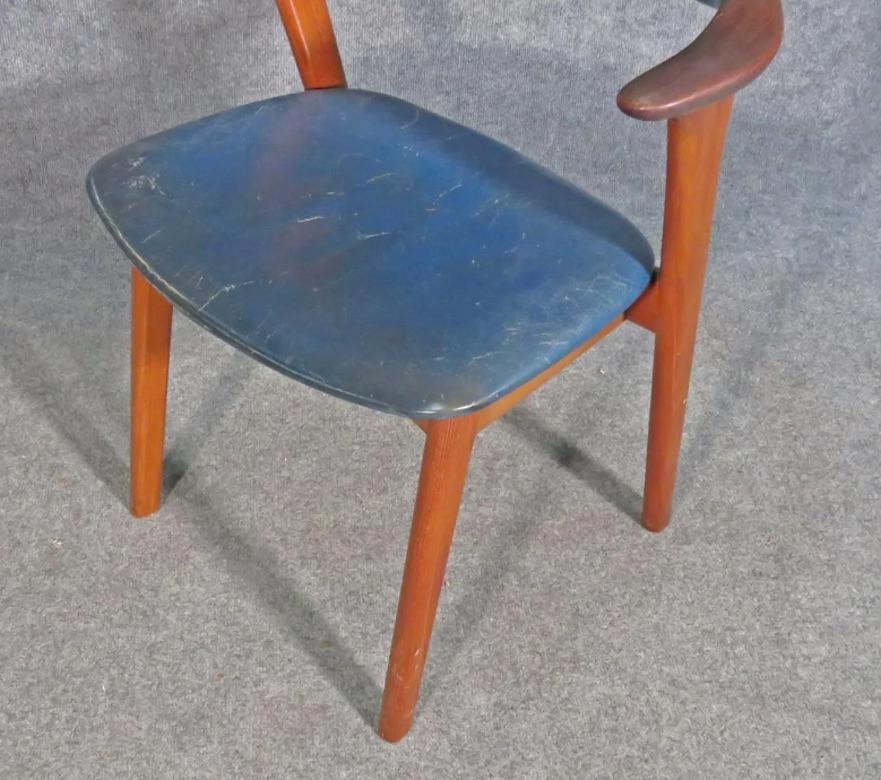 Avec une élégante structure en teck et un revêtement en cuir, cette chaise d'appoint Mid-Century Modern allie un design minimal à des matériaux de qualité. Veuillez confirmer la localisation de l'objet auprès du vendeur (NY/NJ).