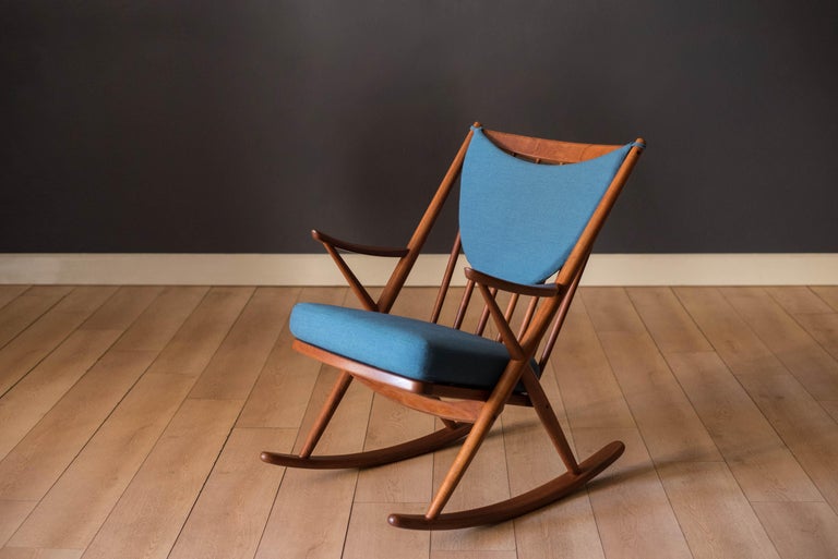 Mid-Century Modern rocker armchair in solid teak designed by Frank Reenskaug for Bramin, circa 1960's. Modern meets traditional with this unique accent chair featuring sculptural armrests and a spindle back chair frame. Newly reupholstered in a