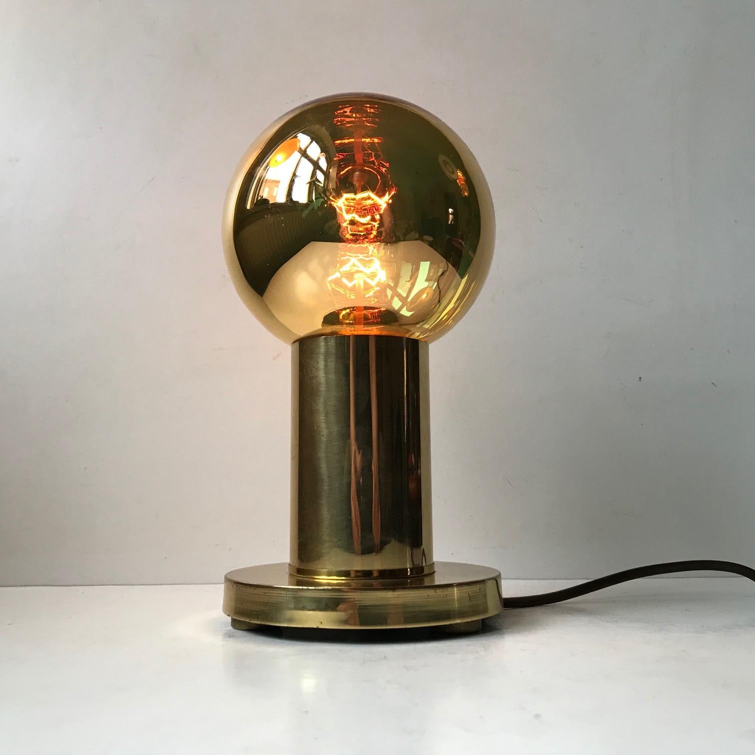 This 'Spy Ball' table lamp was designed and manufactured in the early 1970s by the Danish Design Company Frimann. Featuring a Philips Goldstar 126 everlasting Bulb, the golden bulb reflects its surroundings when unlit, hence the name 'Spy Ball'.
 