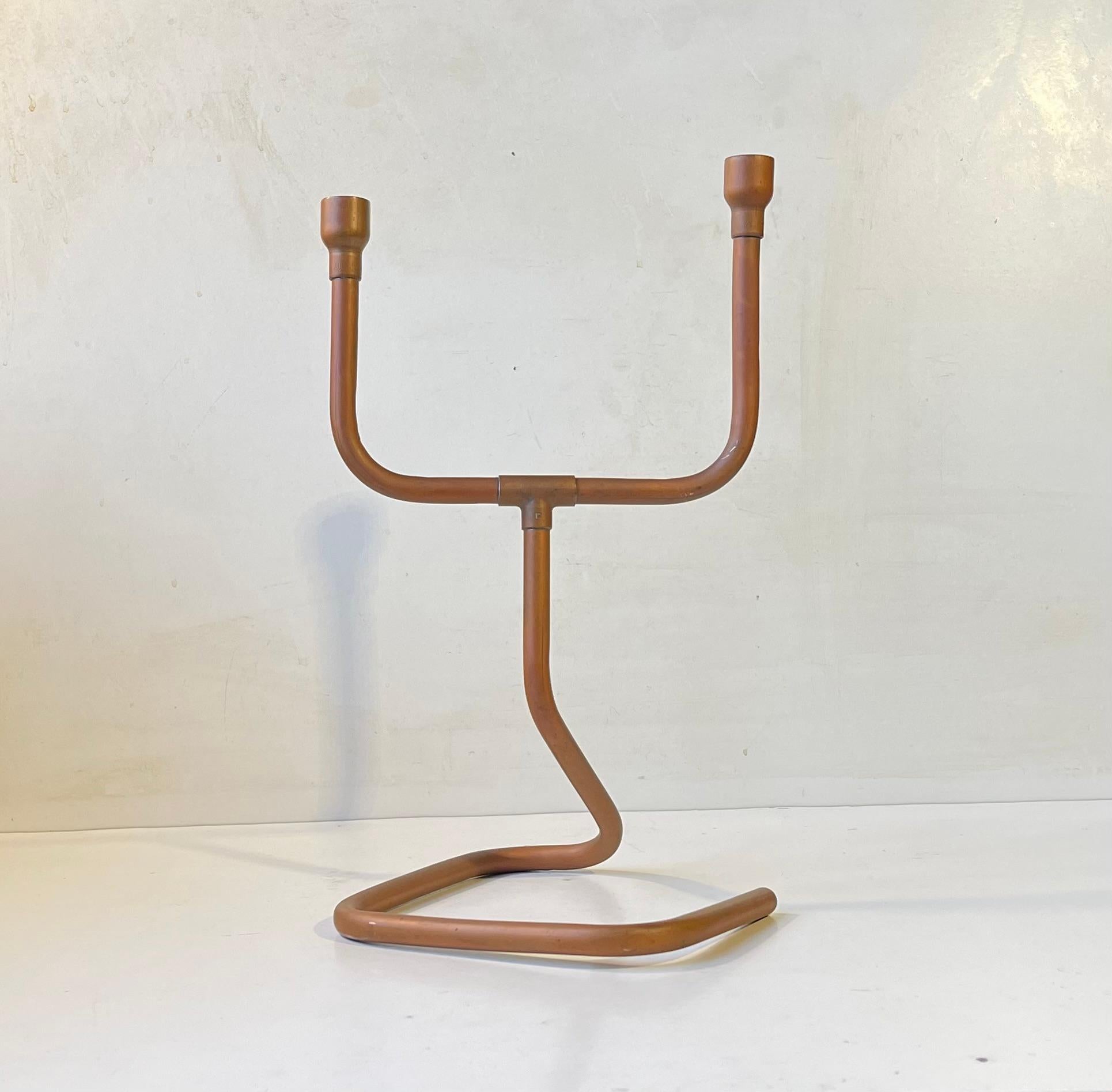 Decorative dual candleholder fashioned from bend solid copper pipes. Naturally patinated over the years. Anonymous danish metal worker/artist circa 1970. It is to be fitted with regular sized candles. Measurements: H: 33/31.5 cm, W: 19 cm, Dept: 21