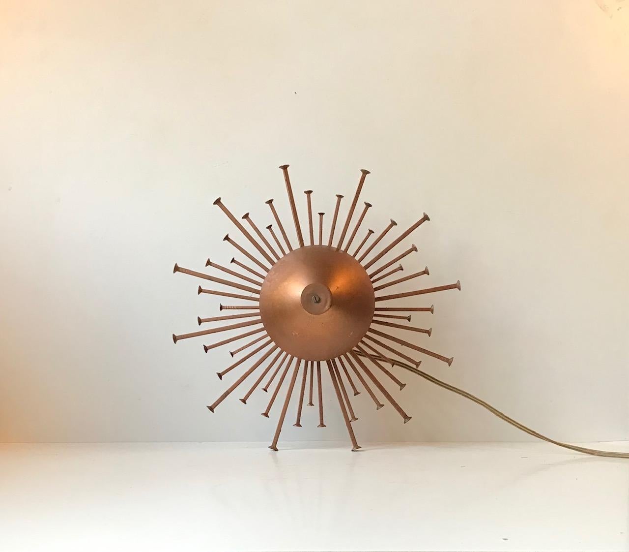 Sculptural iron sconce depicting a bursting sun or star. Lacquered with copper powder coating. Manufactured and designed in Denmark by Dantoft during the 1970s.