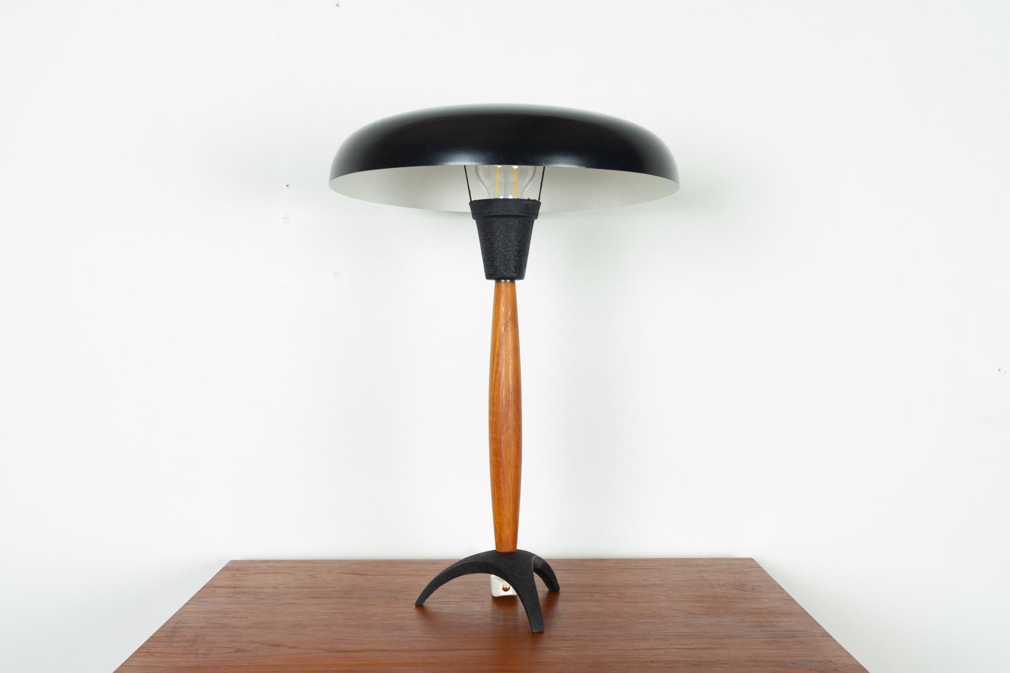Vintage Danish table lamp 1960s
Space age desk lamp in teak and metal. Black tripod base with teak stem. Mushroom shaped shade in black aluminium. 
E26/27 socket. Switch on the cord.
Good vintage condition. Small dings and scratches on the shade.