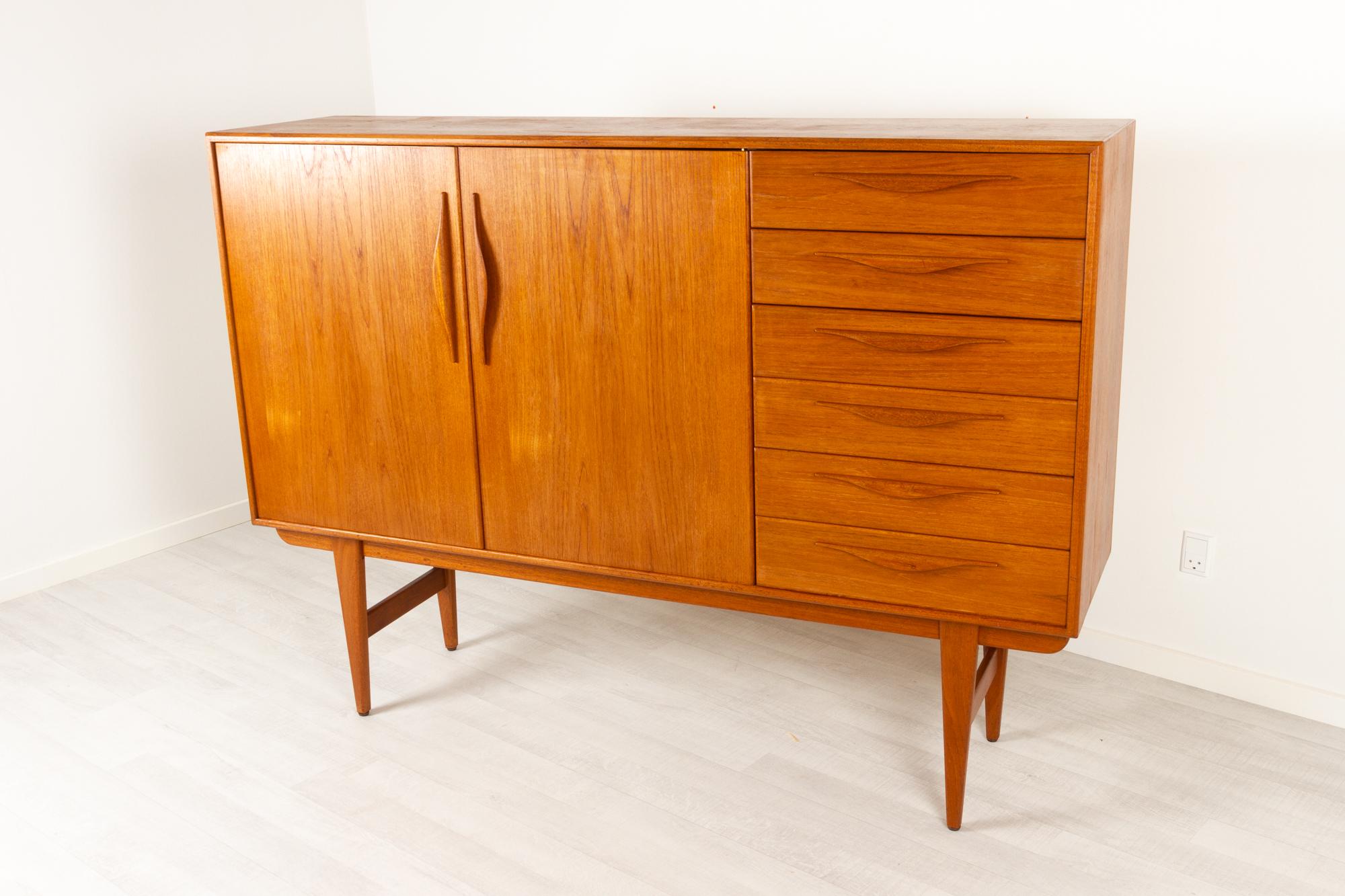 Vintage Danish tall teak sideboard, 1960s
Very elegant Danish modern highboard. Six drawers with pulls in sculpted solid teak. Top drawer lined with green felt. Large compartment with double hinged doors, also with pulls in solid teak and two full