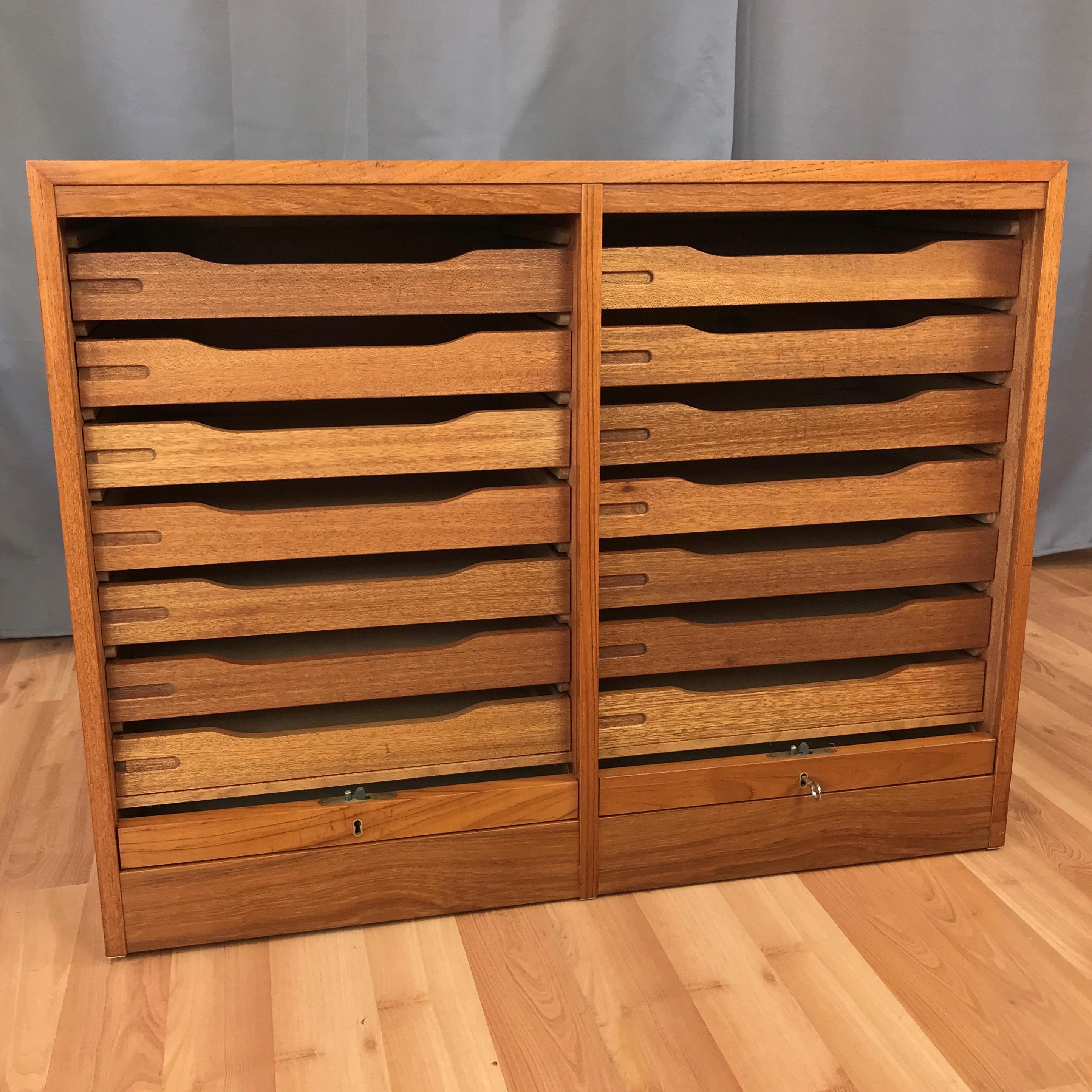 A vintage Danish dual compartment teak file cabinet with locking tambour doors.

Very clean design features smooth front tambour doors that roll down into the base and out of sight. Each side features seven shallow drawers with pine bottoms.