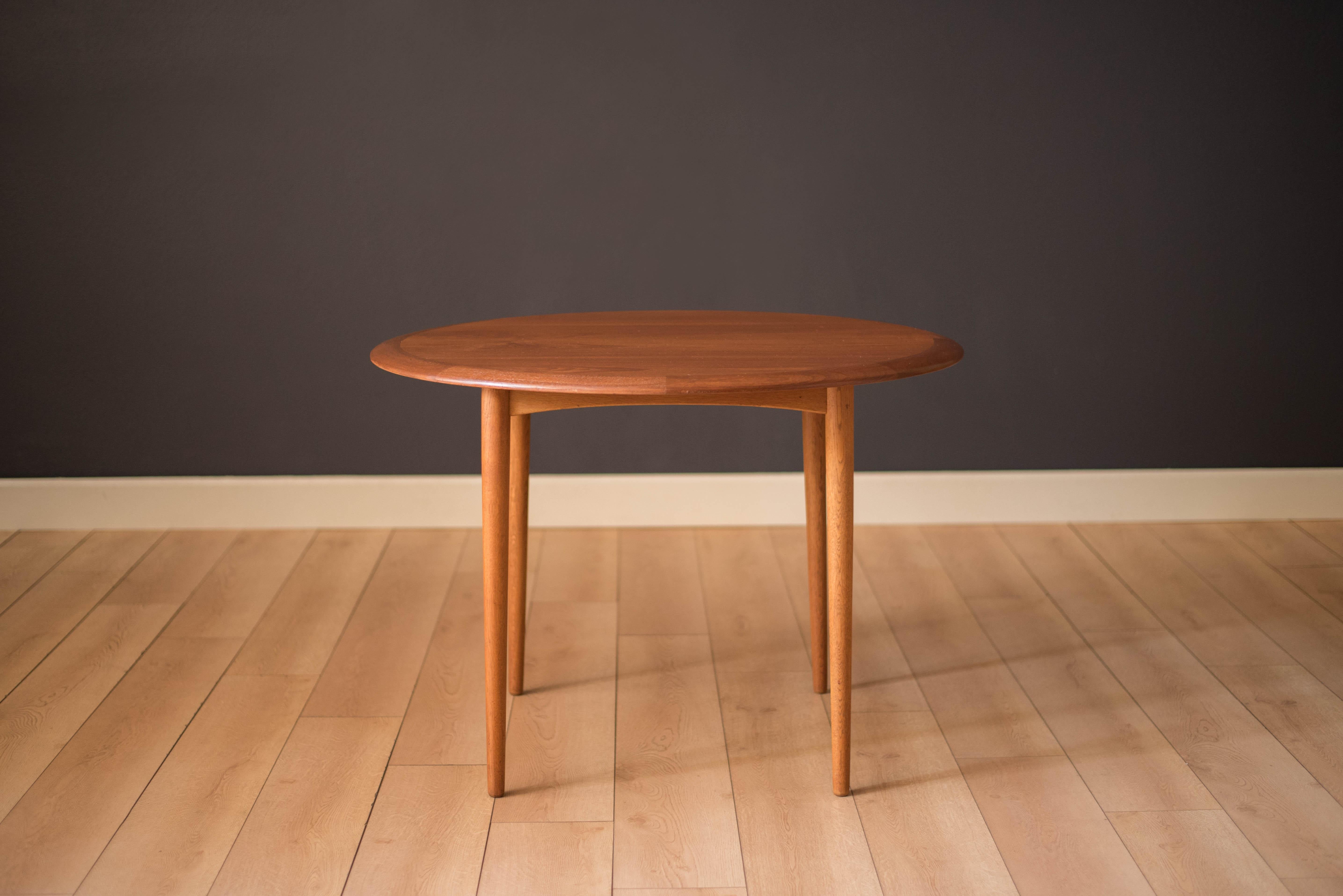 Mid-Century Modern round dining table in teak, circa 1960s, Denmark. This simple design seats up to four people and is perfect to use as a card game table. The tabletop features thick solid teak edge banding and is supported by contrasting oak