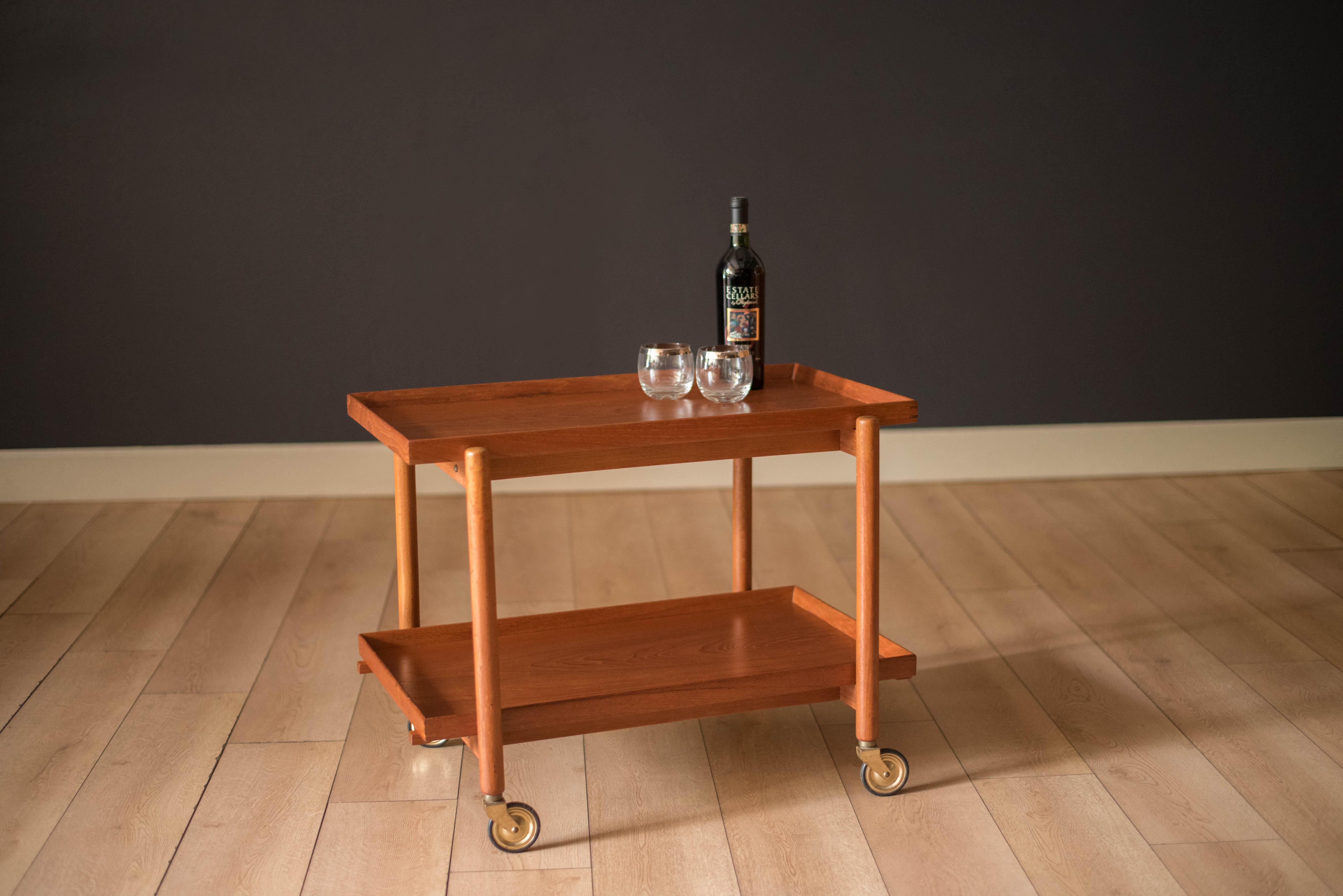 Mid century modern bar cart designed by Poul Hundevad circa 1960's. This versatile piece features natural teak grains including two serving trays with detailed finger joinery. Bottom tray is adjustable to double up the surface area on top.

Each
