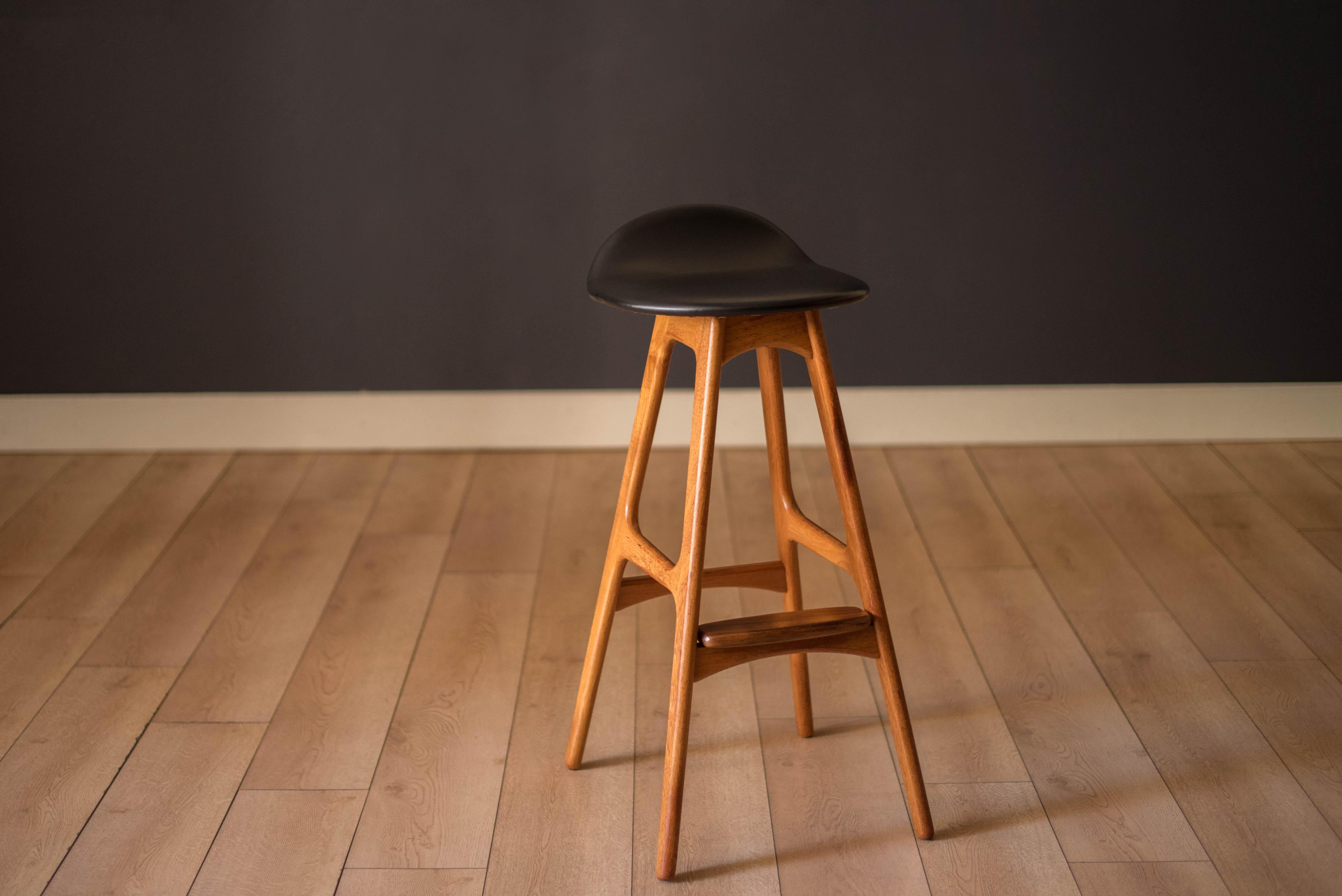 Mid Century Modern counter stool in teak designed by Erik Buch for O.D. Mobler. Features a black vinyl seat equipped with a curved backrest support and integrated foot pedal. This piece works perfectly in the kitchen, bar, and dining area.



